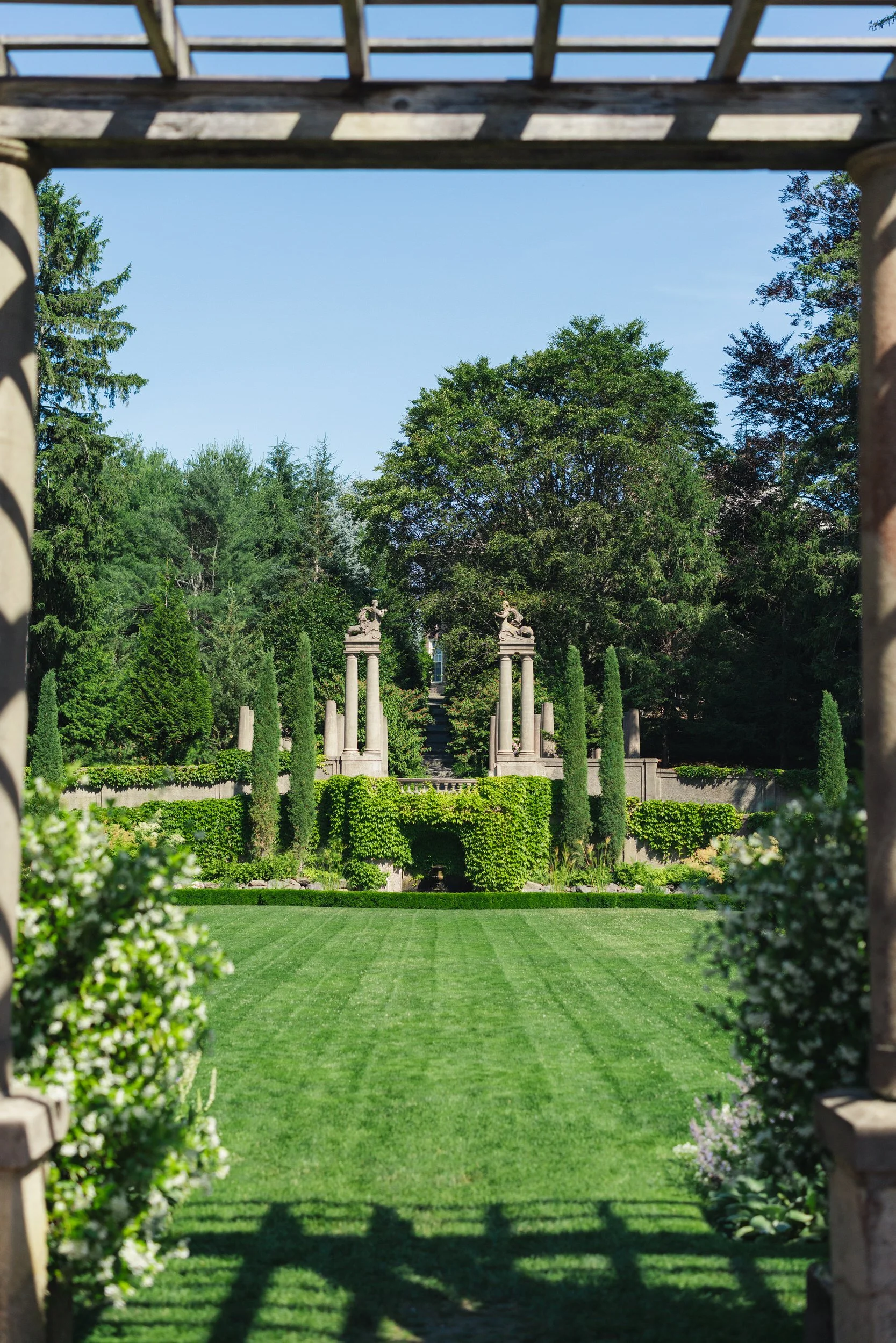 Romantic garden ceremony setup in the Italian Garden at Crane Estate surrounded by lush summer landscaping.
