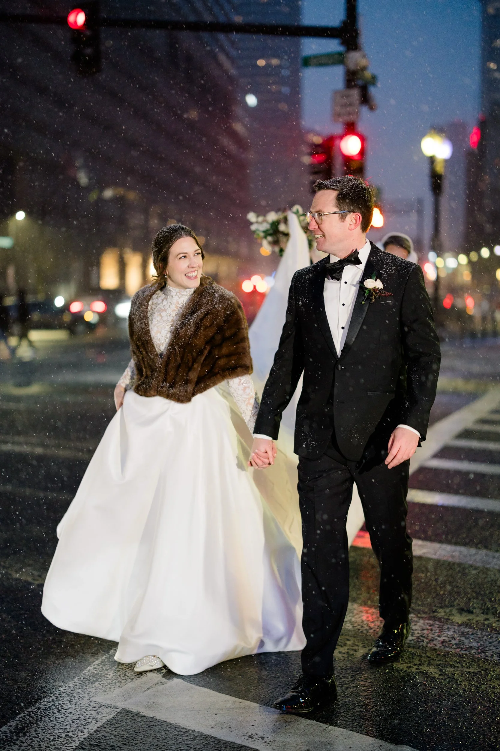 Bride and groom walk hand in hand in snow at Fairmont Copley Hotel Wedding