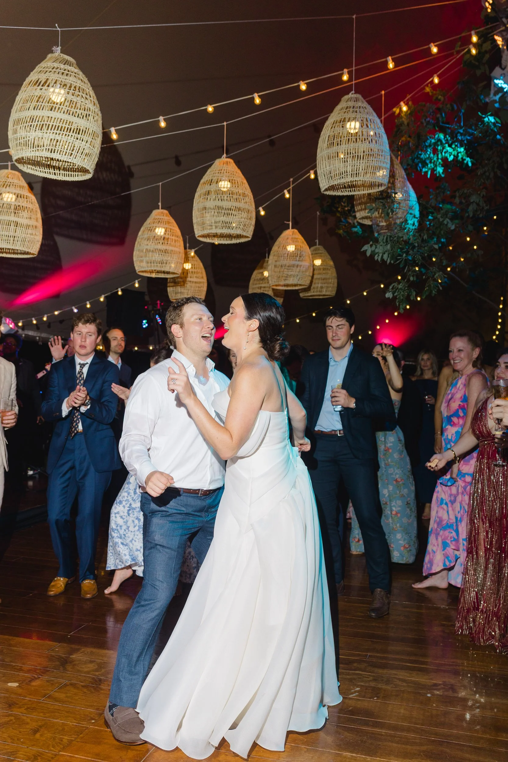 Guests dancing beneath colorful floral installations and full-scale trees at the reception.