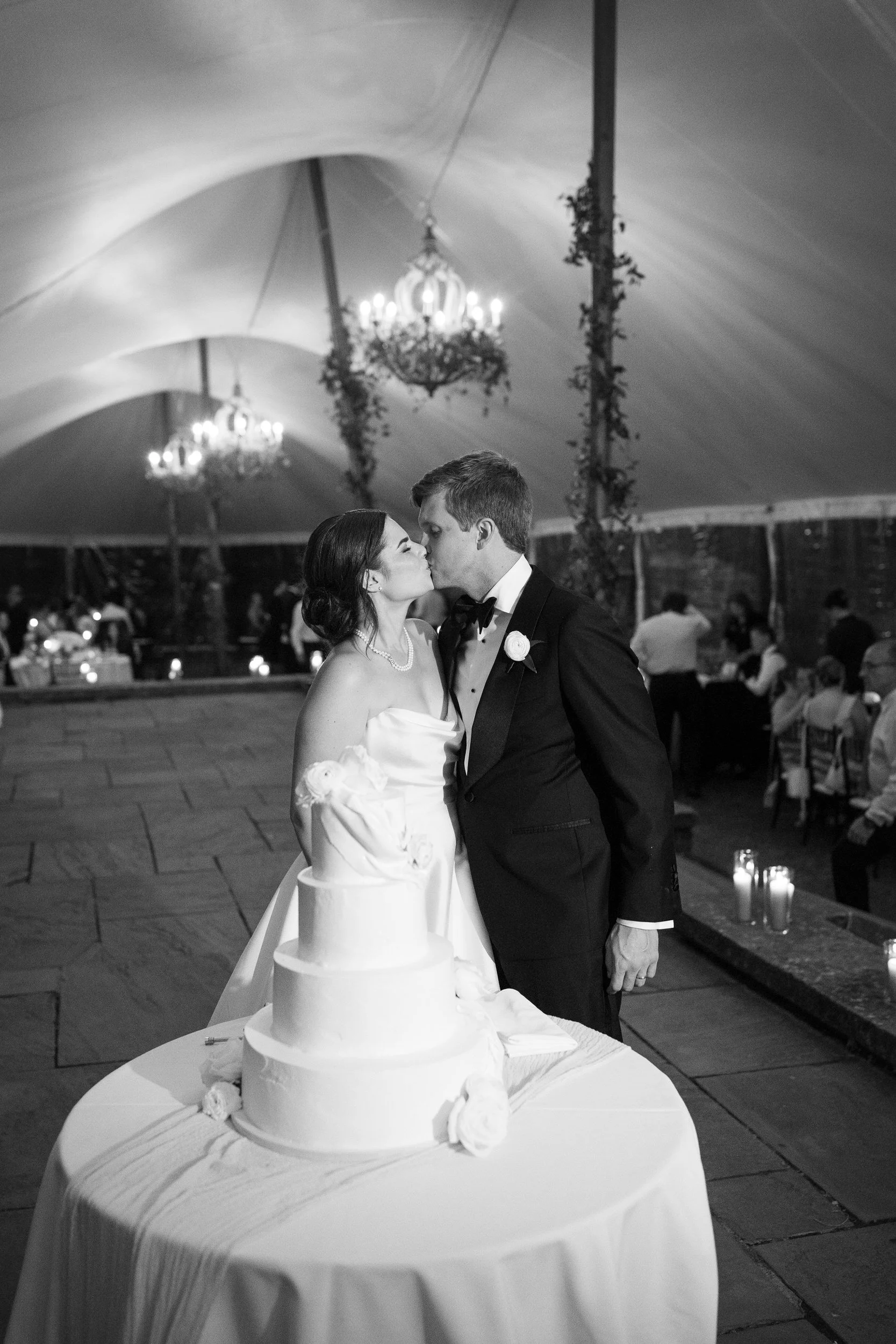 Romantic cake cutting moment captured inside the sailcloth tent at a Crane Estate wedding reception.