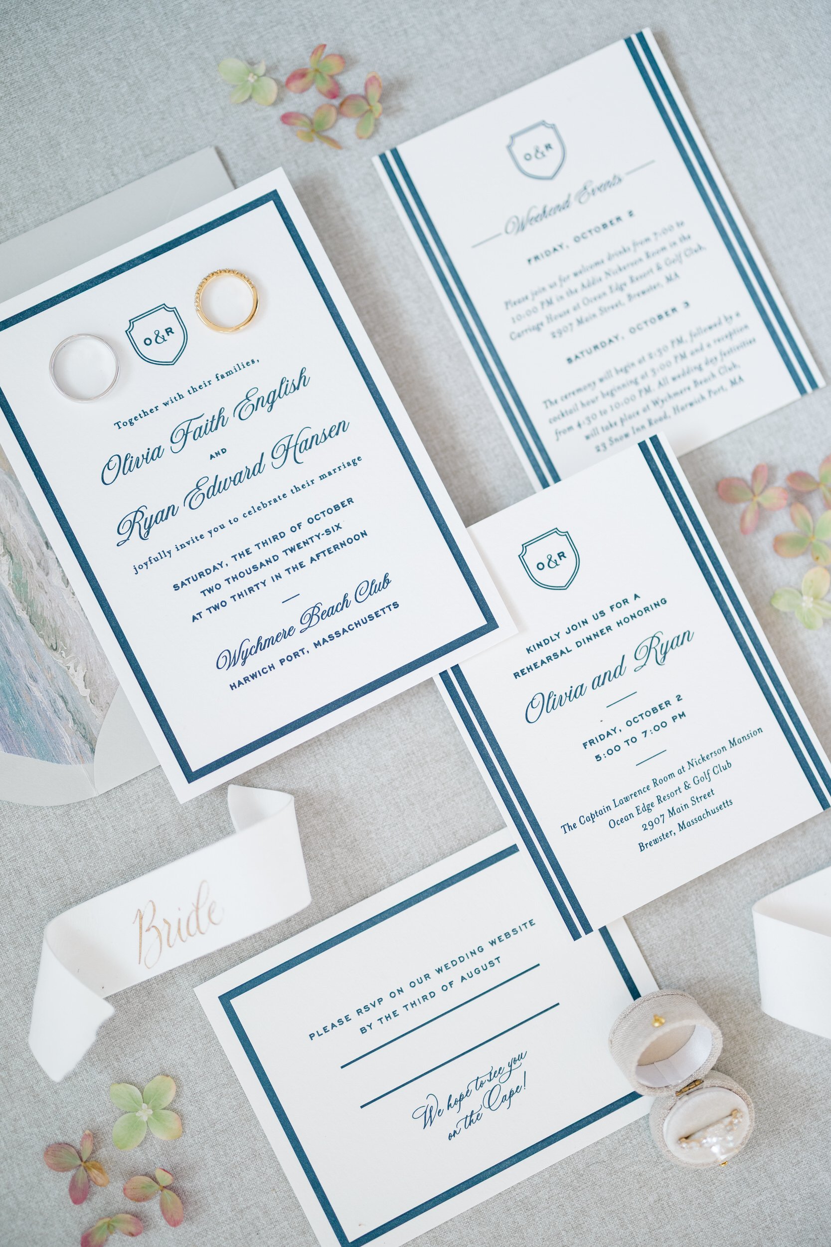 Editorial flat lay of wedding rings, paper goods, and accessories at a Cape Cod wedding.