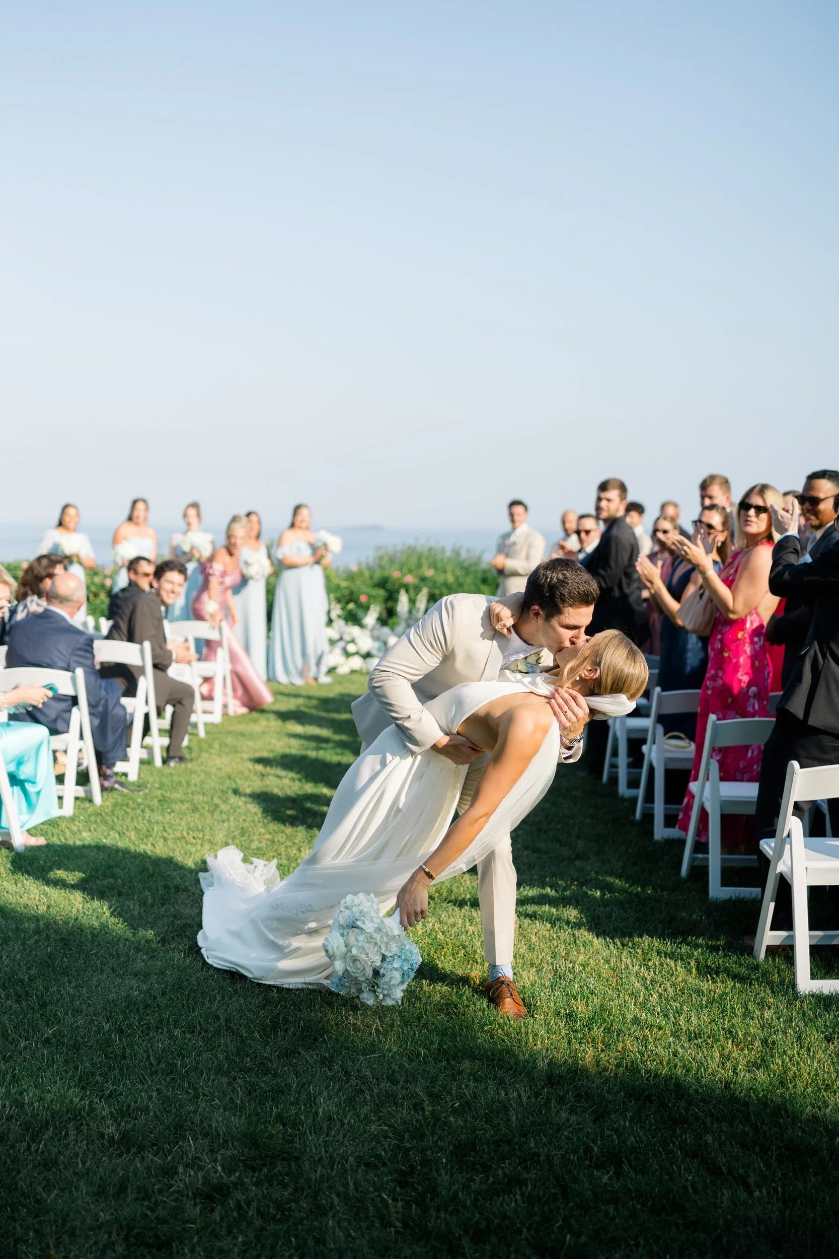 Couple sharing their first kiss as newlyweds during a coastal wedding ceremony.