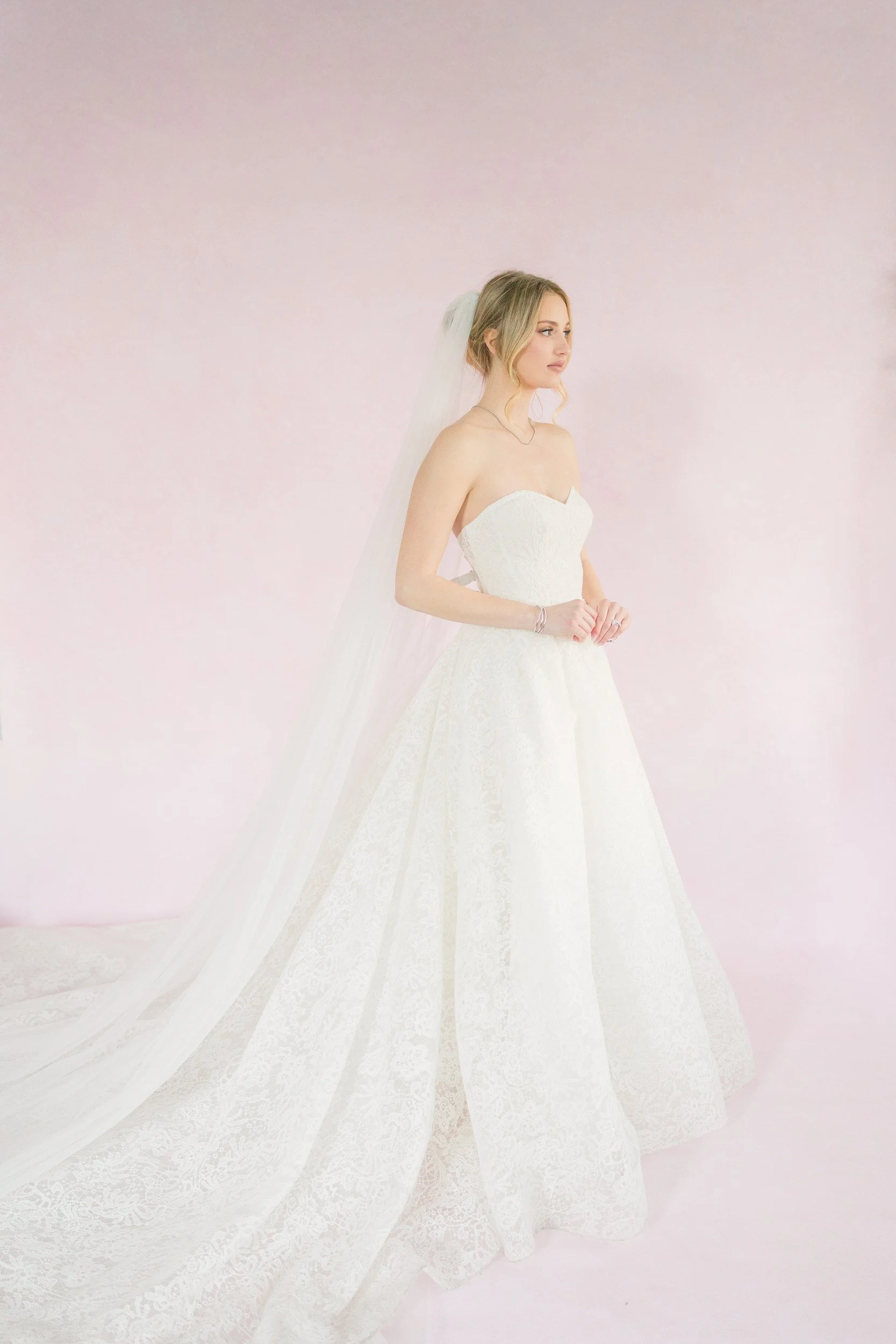 Bride getting ready in front of a pastel pink backdrop at The Gadsen House in Charleston, South Carolina