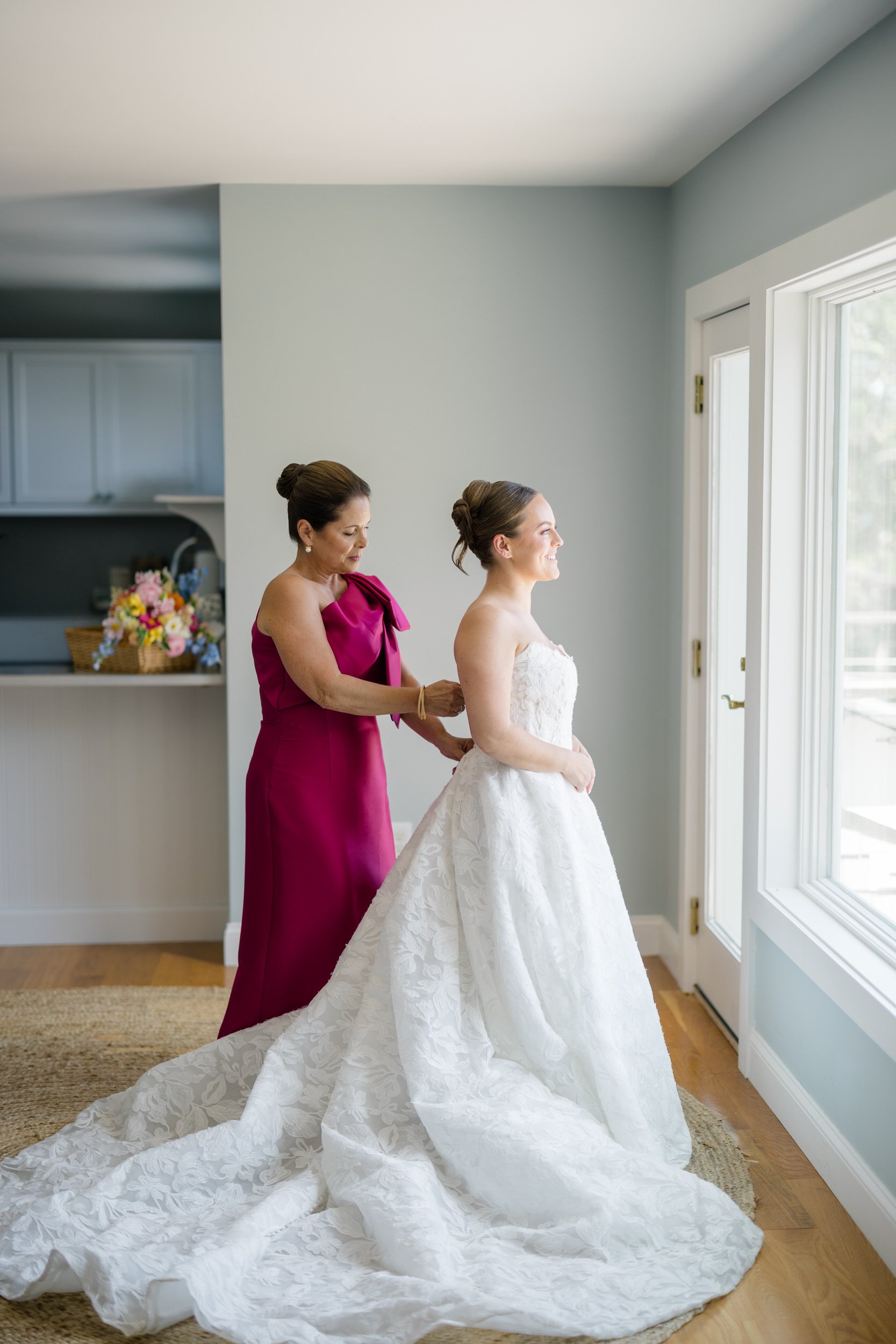 Bride putting on her Jenny Yoo wedding dress at her family's Cape Cod waterfront home.