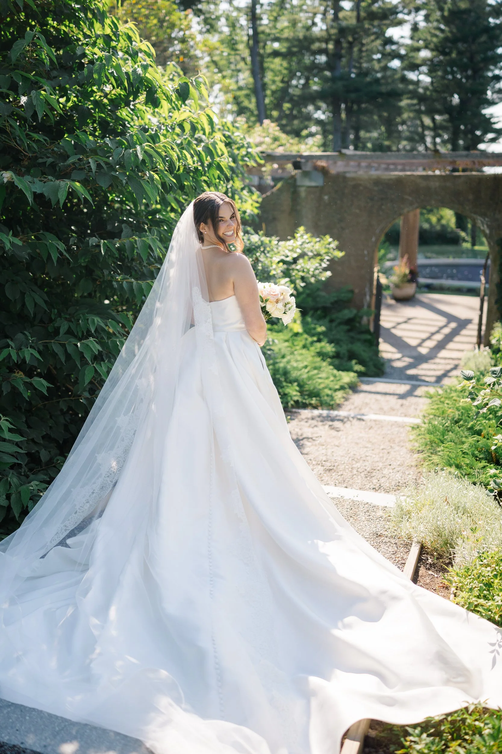 Bride revealing her Monique Lhuillier gown to the groom during a romantic first look in the Castle Hill Rose Garden.