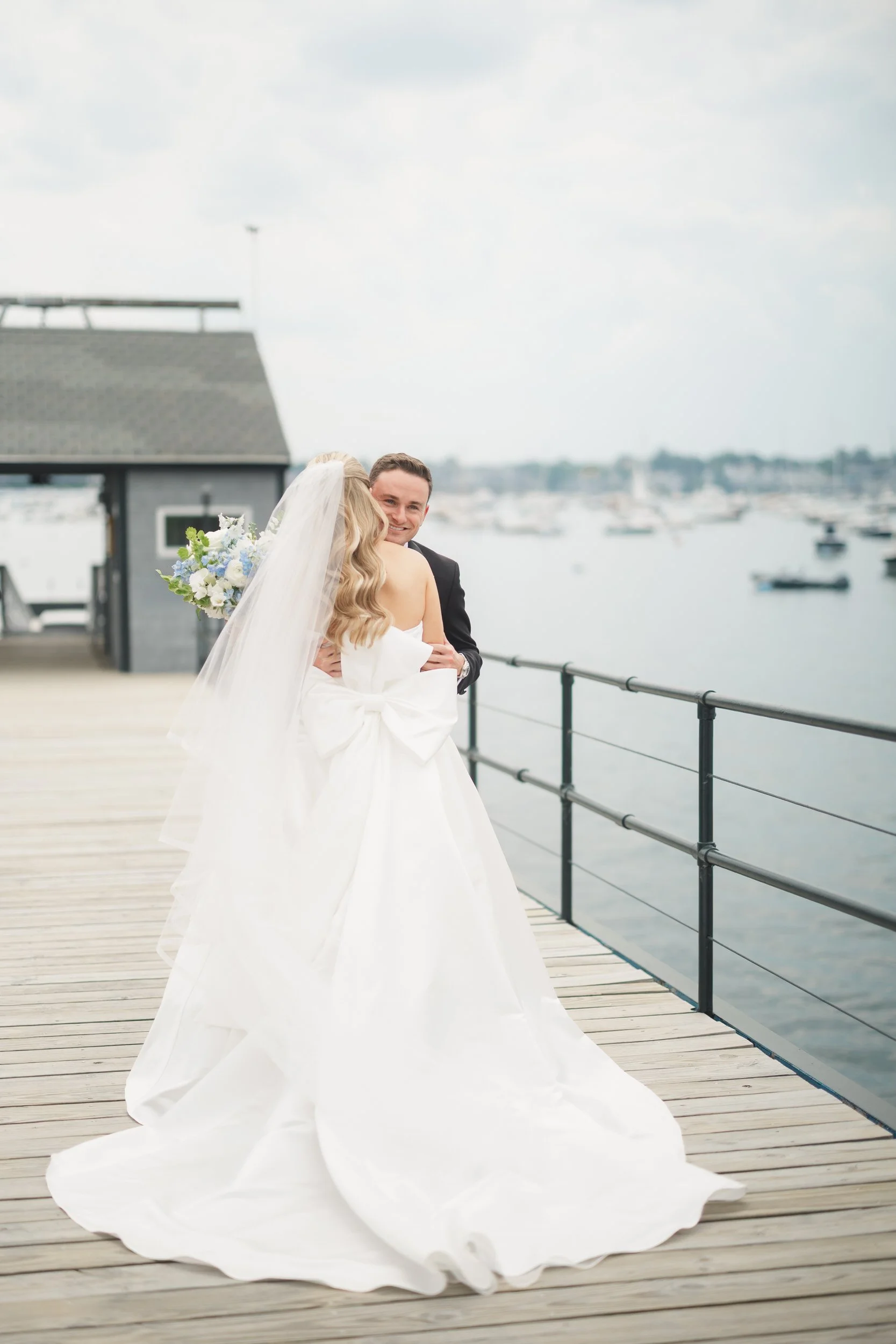 Bride and groom first look at Marblehead Harbor surrounded by hundreds of sailboats.