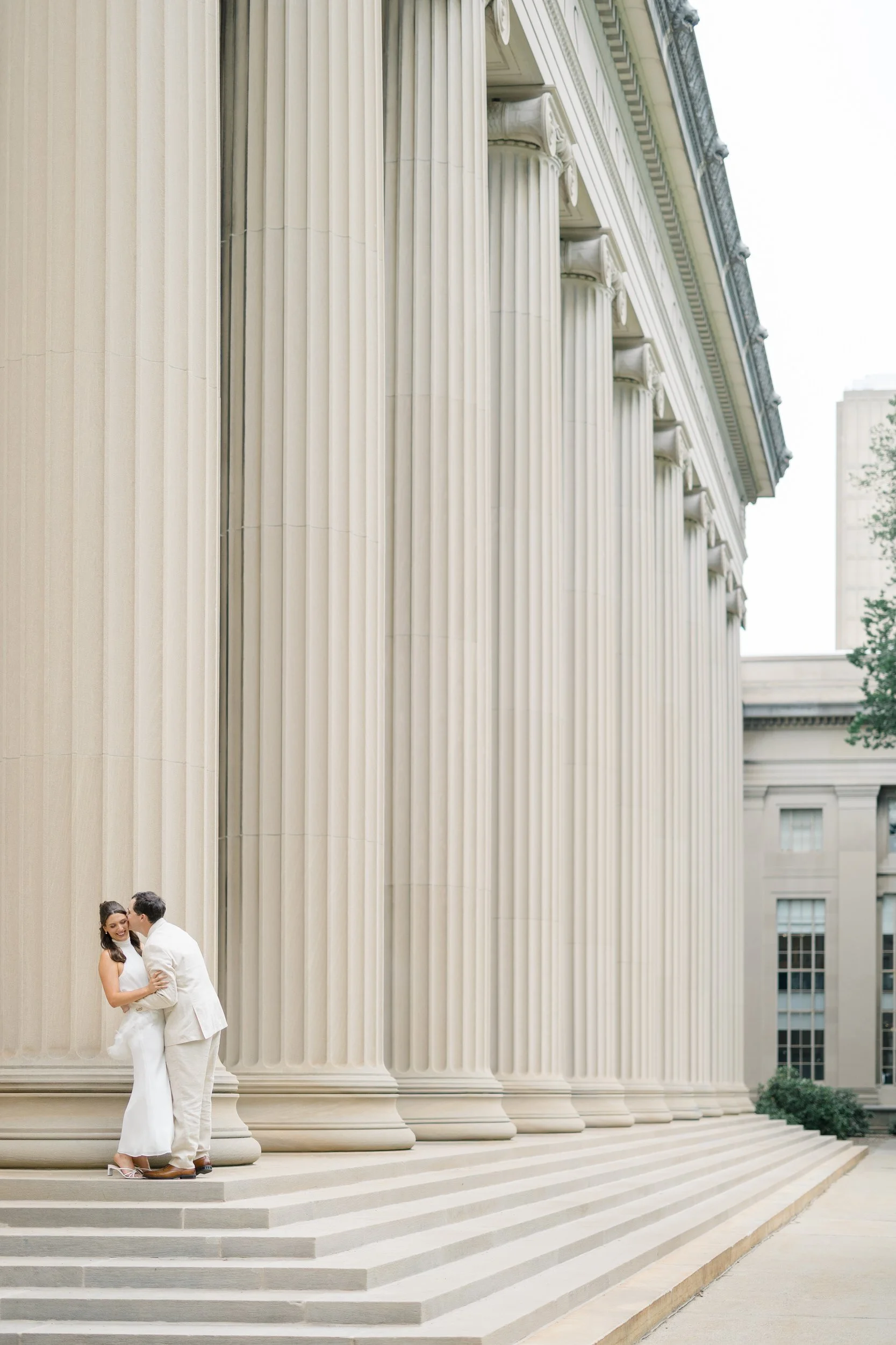 Couple embracing beneath marble columns during a classic Boston engagement session.