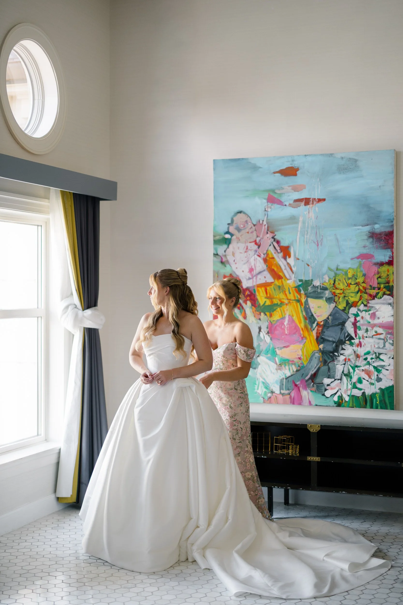 Bride putting on her wedding gown at Hotel Commonwealth before a garden wedding celebration