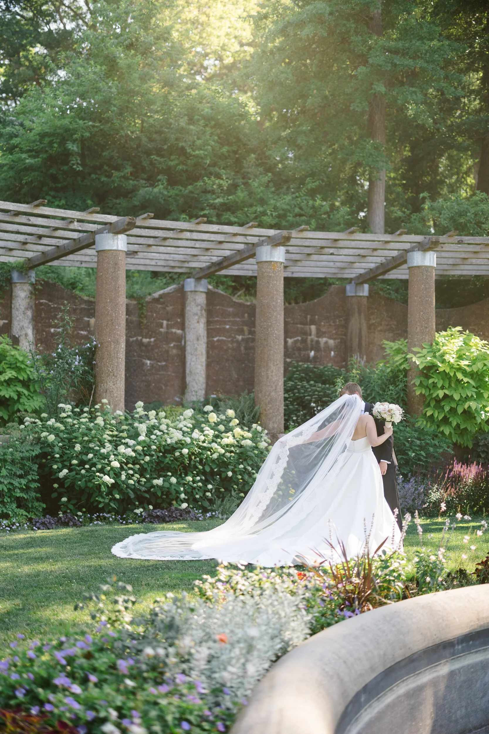 Couple sharing an emotional embrace during their first look surrounded by roses at Crane Estate.