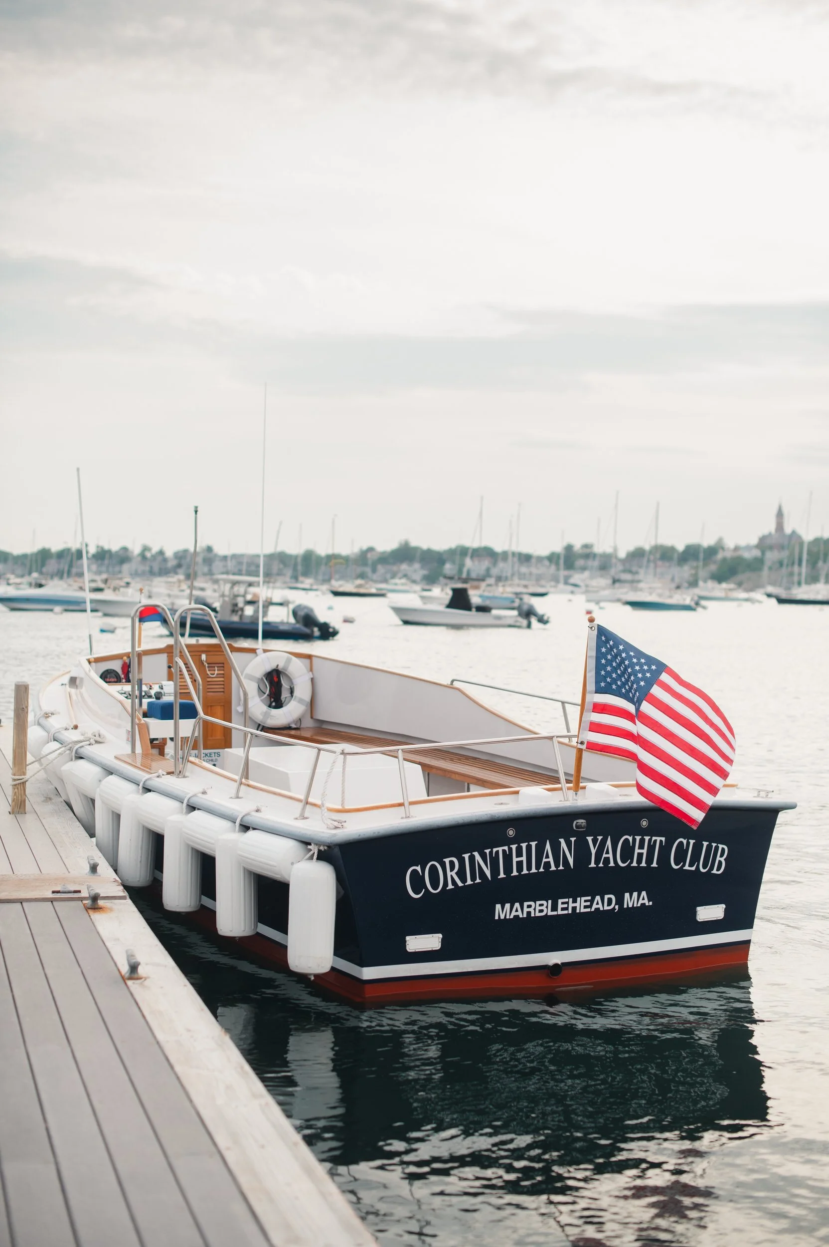 Sunset boat portraits of bride and groom in Marblehead Harbor surrounded by sailboats during their wedding celebration.