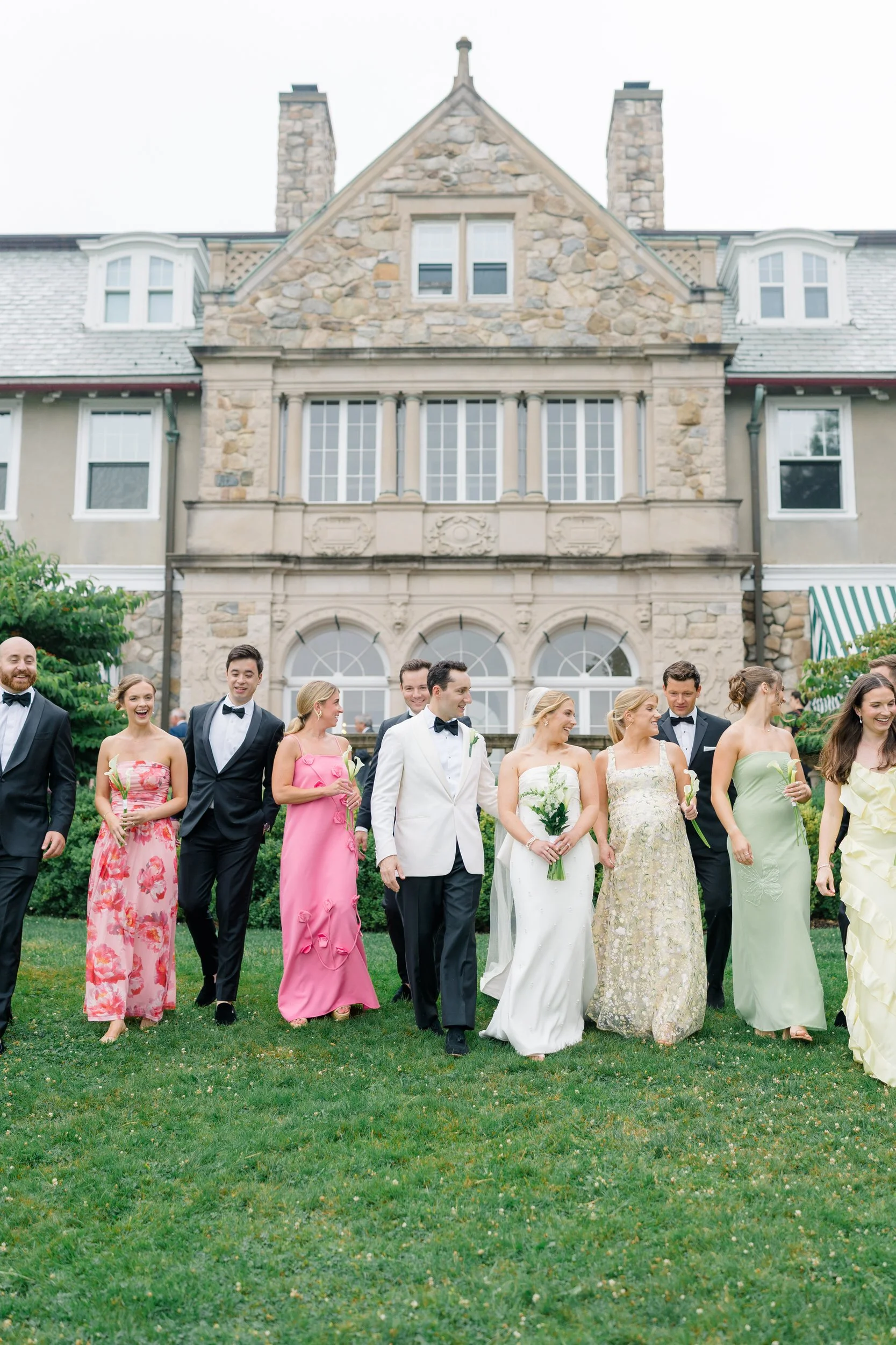 Wedding party laughing together outside Blithewold Mansion.