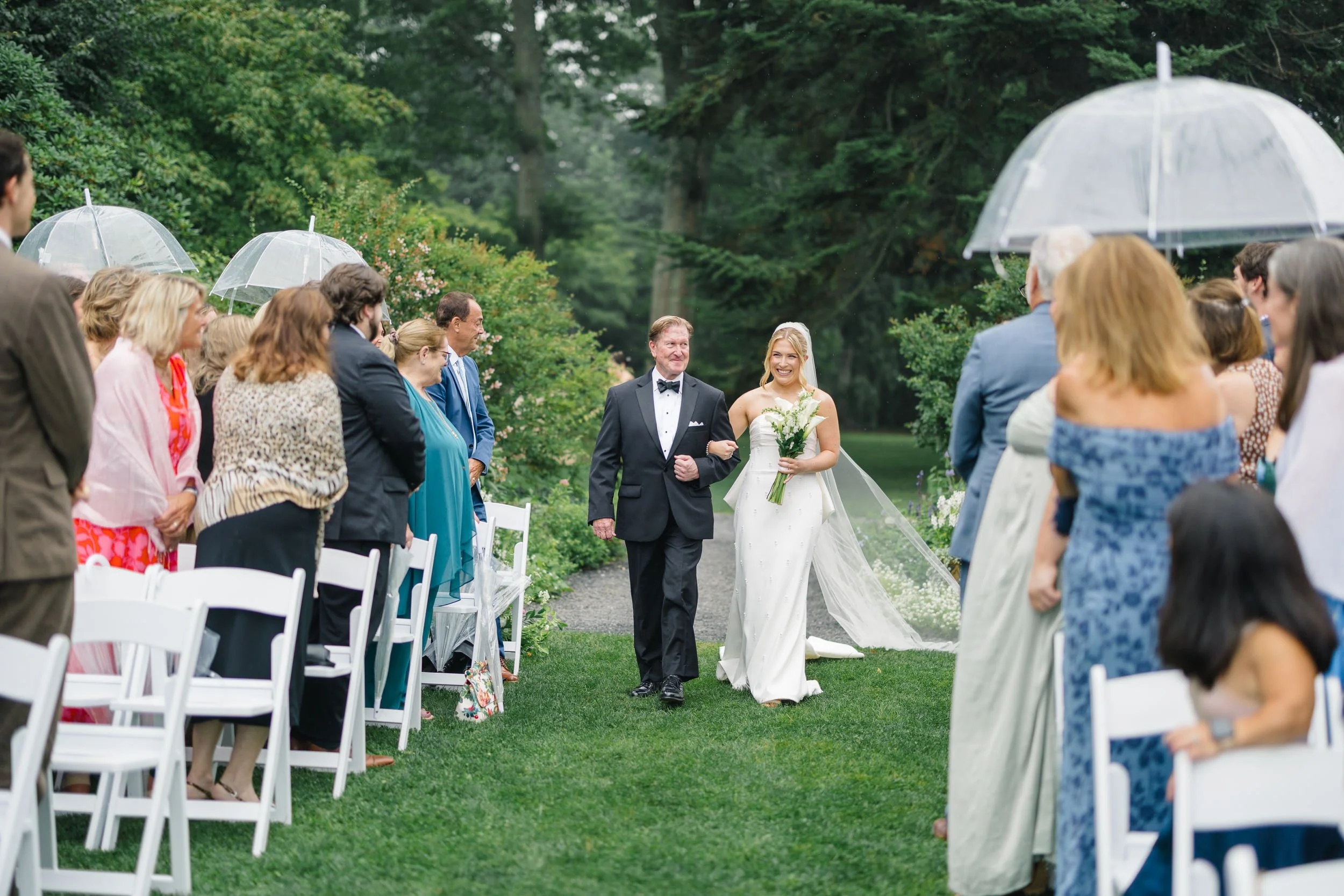 Bride walking down the aisle in a cathedral veil during a rainy Rhode Island wedding.