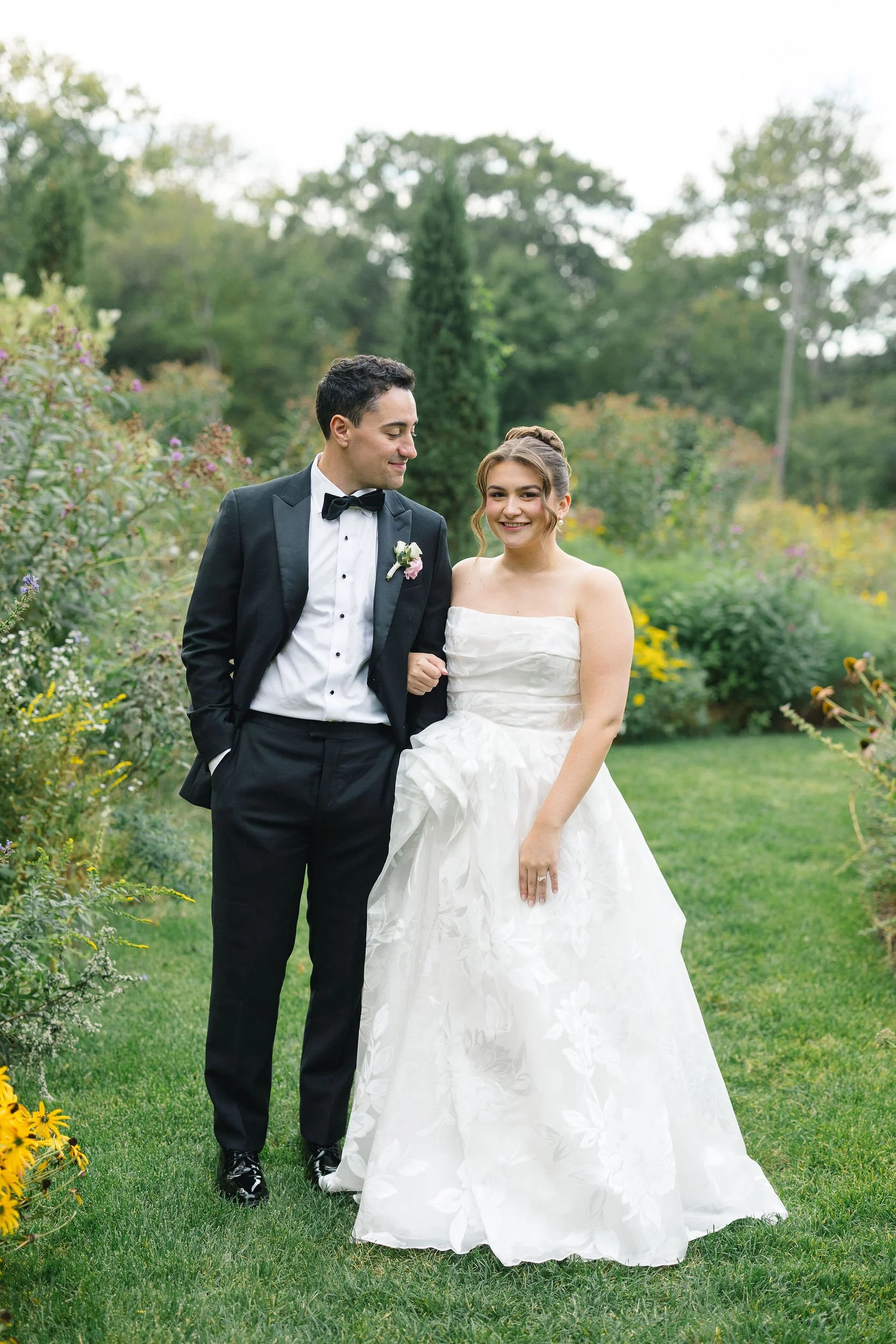 Newlyweds walking together through the Long Hill estate grounds at sunset.