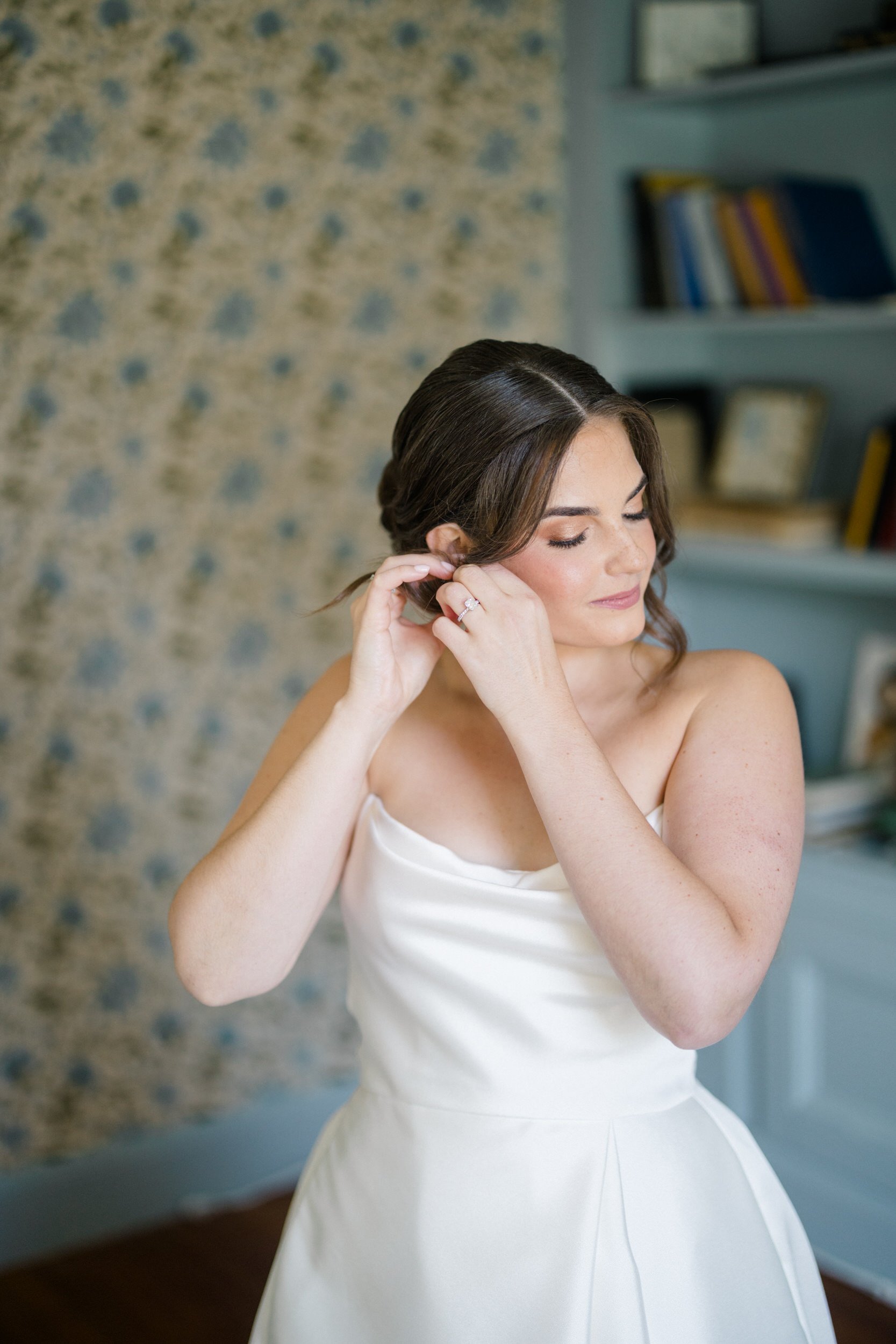 The bride fastening her earrings before her elegant wedding celebration at Crane Estate.