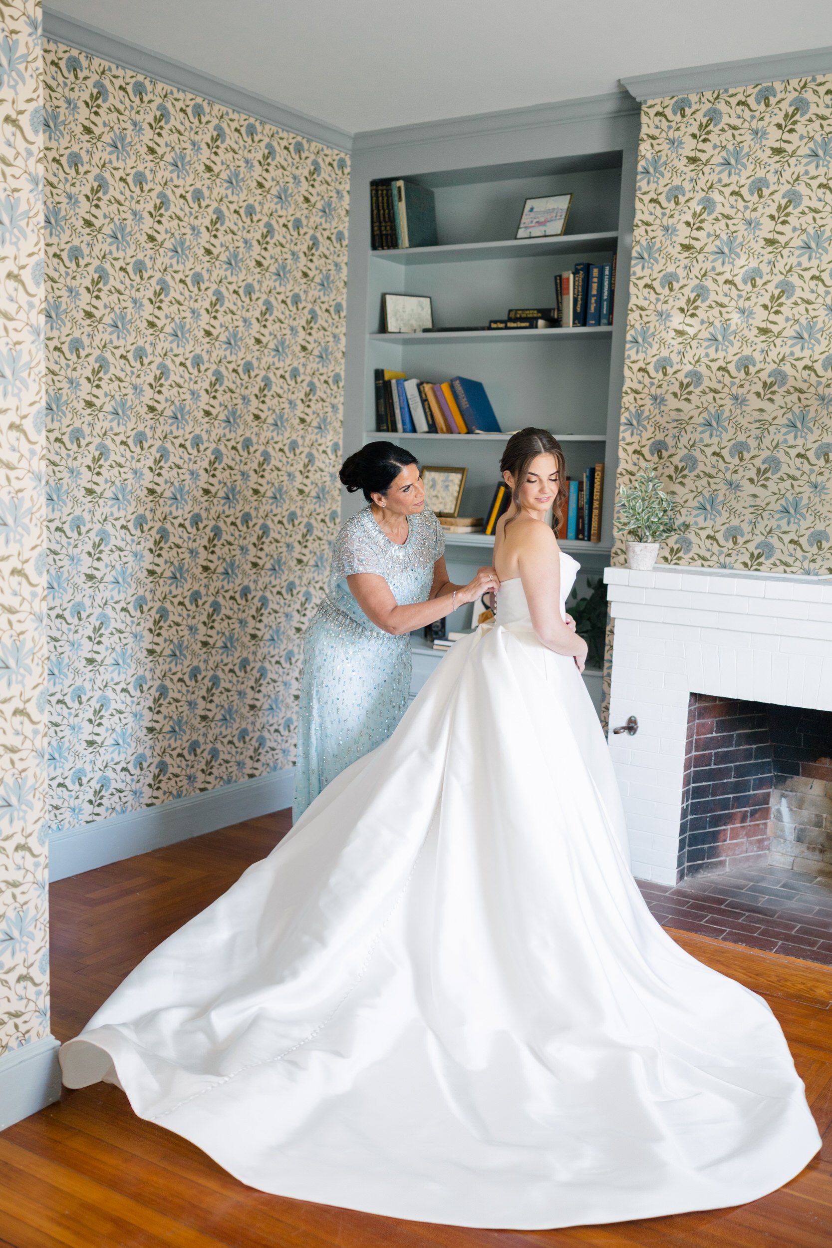 The bride stepping into her Monique Lhuillier wedding gown at the Ipswich Inn surrounded by her closest friends.