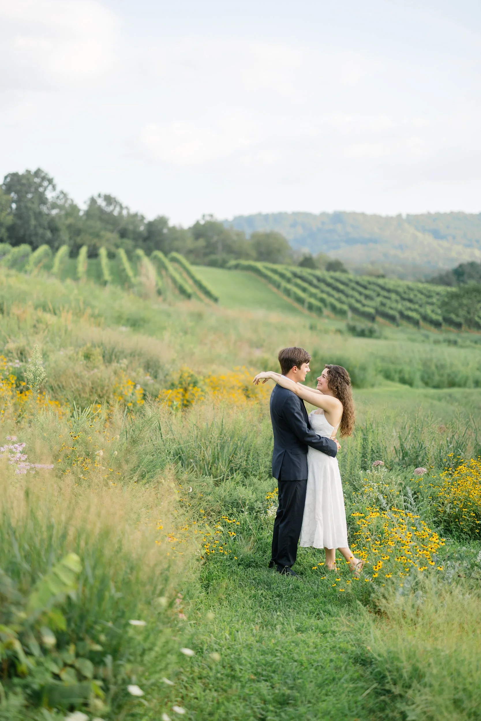 Couple embracing with the Virginia vineyard in the background at Pippin Hill
