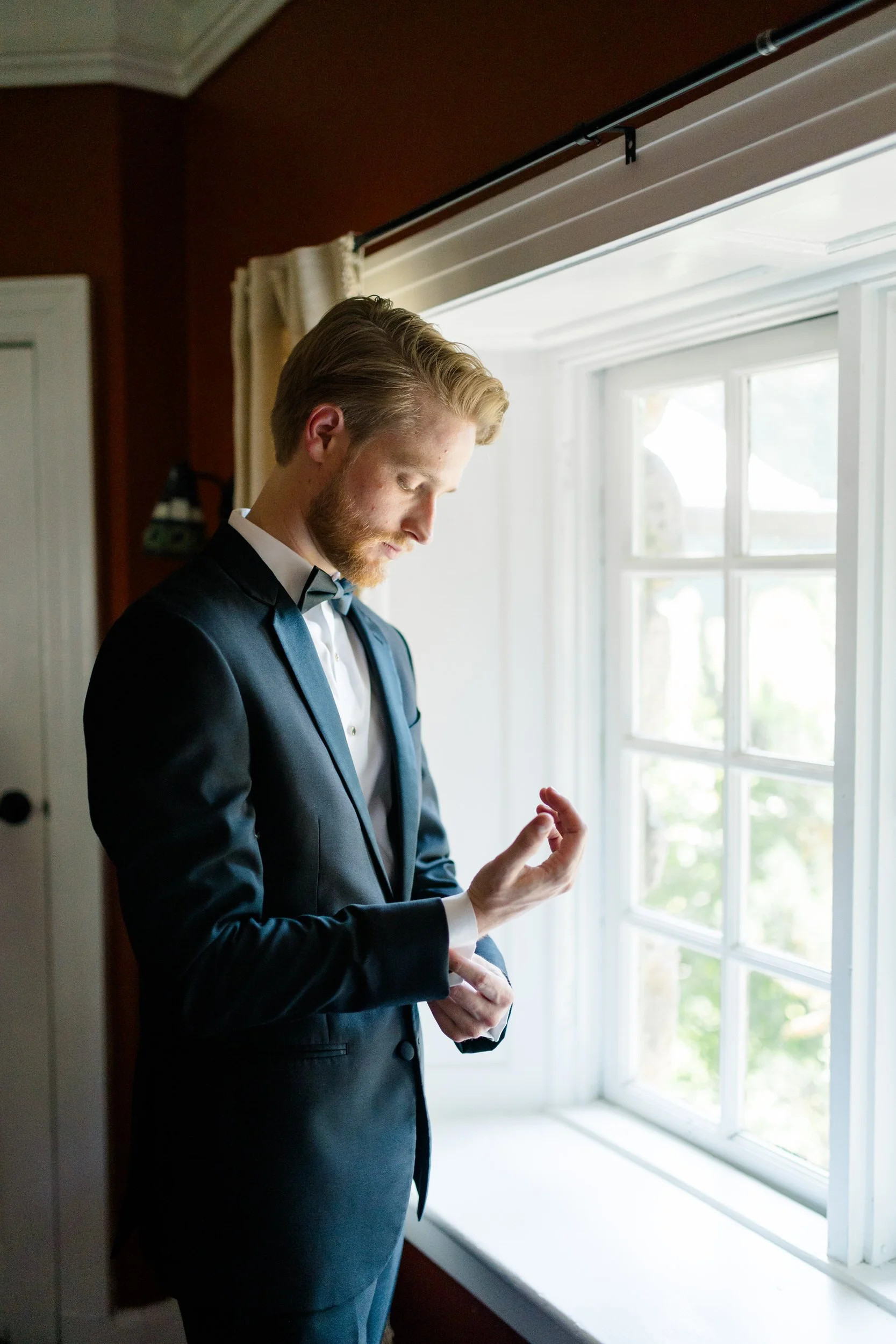 Groom getting ready in black suit and bow tie at Willowdale Estate wedding in Massachusetts