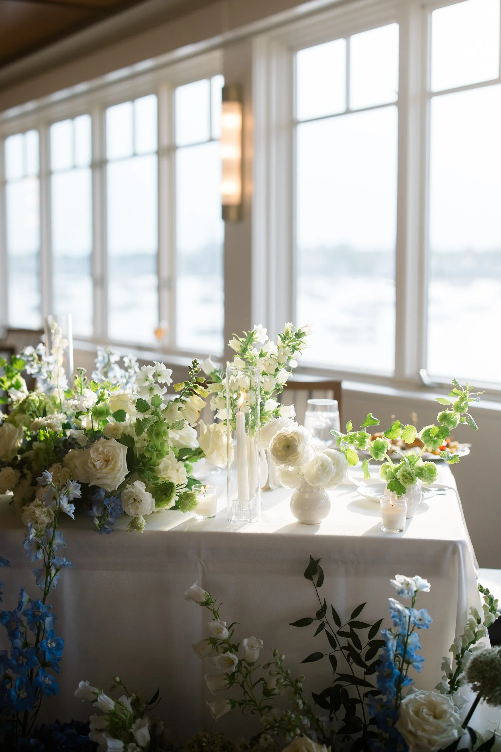Coastal wedding reception tables styled with hydrangeas, dogwoods, and lily of the valley at a Marblehead Massachusetts waterfront venue.