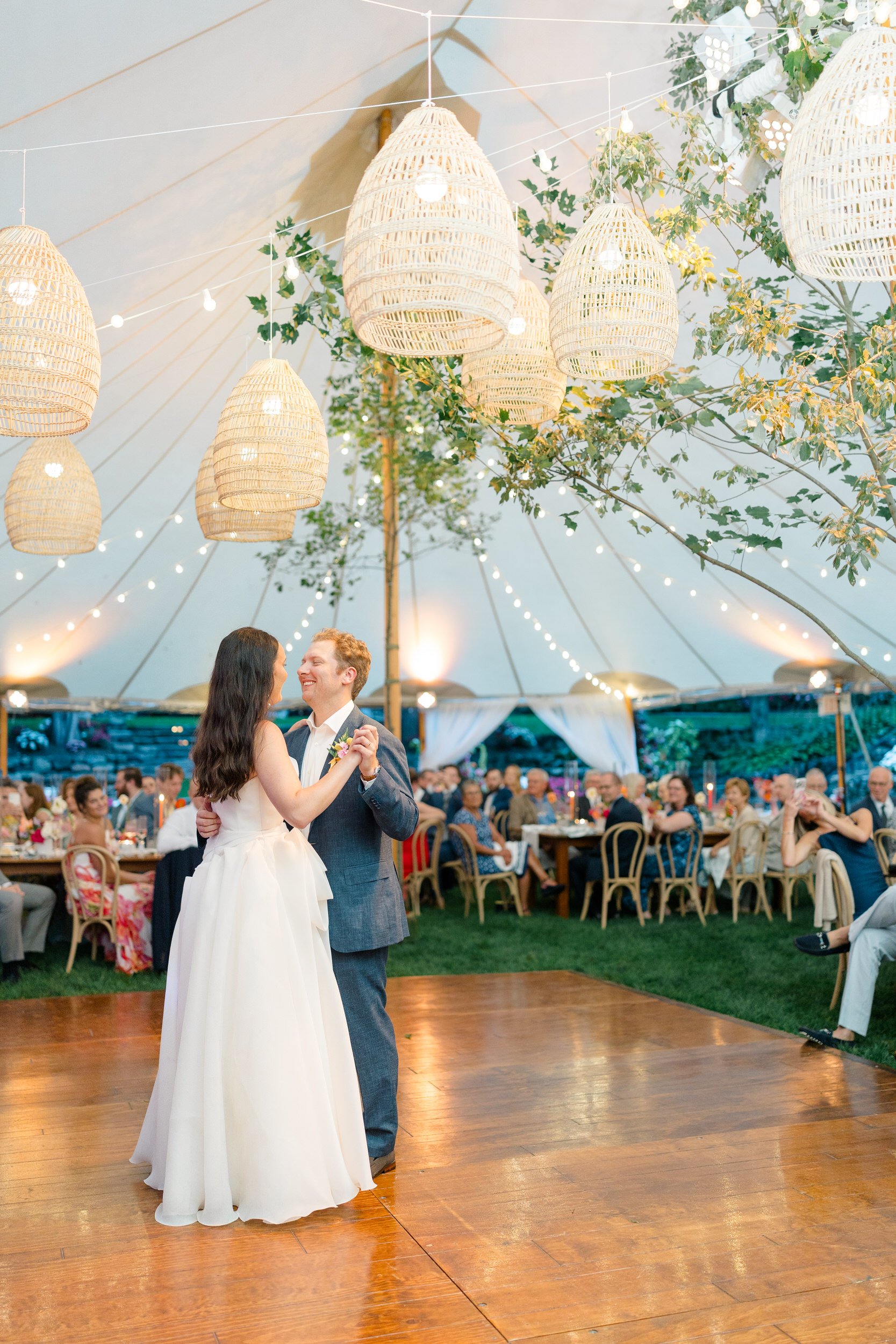 Newlyweds sharing their first dance beneath colorful floral installations at the Connors Center.