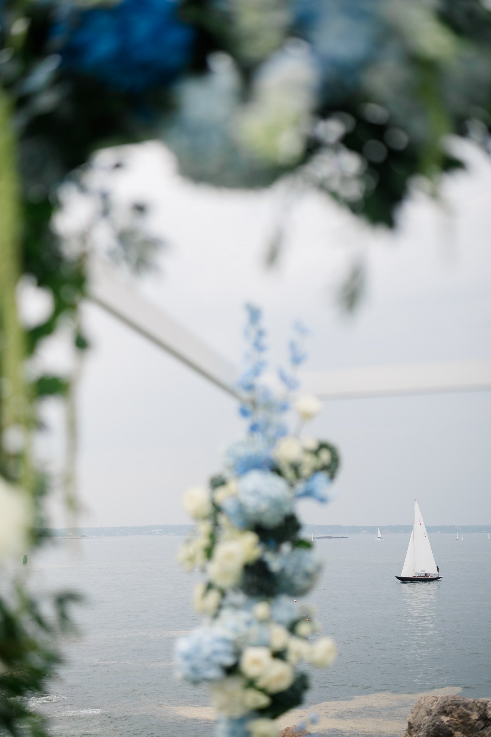 A modern chuppah installation with hanging amaranthus at a Marblehead Massachusetts waterfront wedding ceremony.