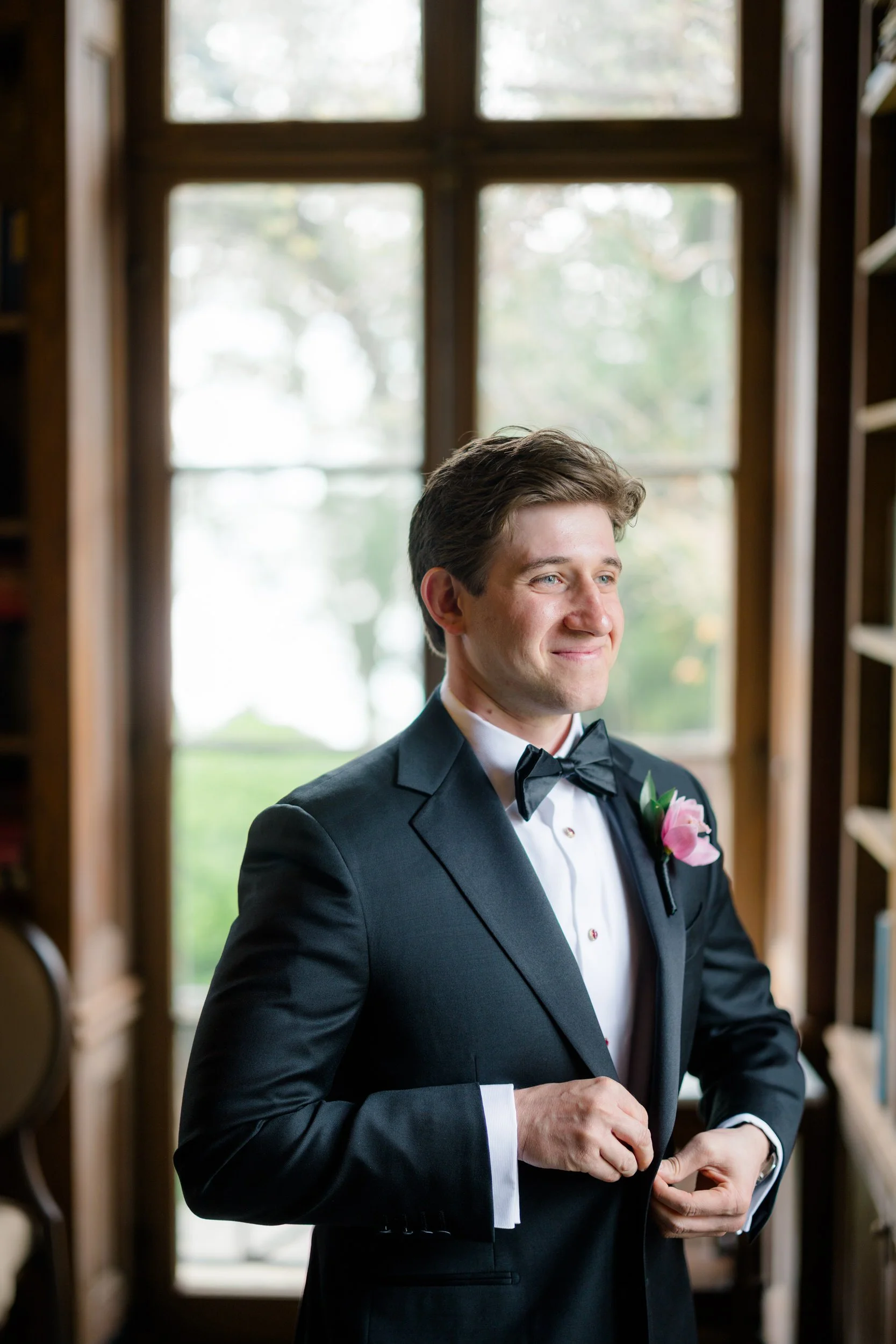 Groom getting ready in wood library at Misselwood Estate