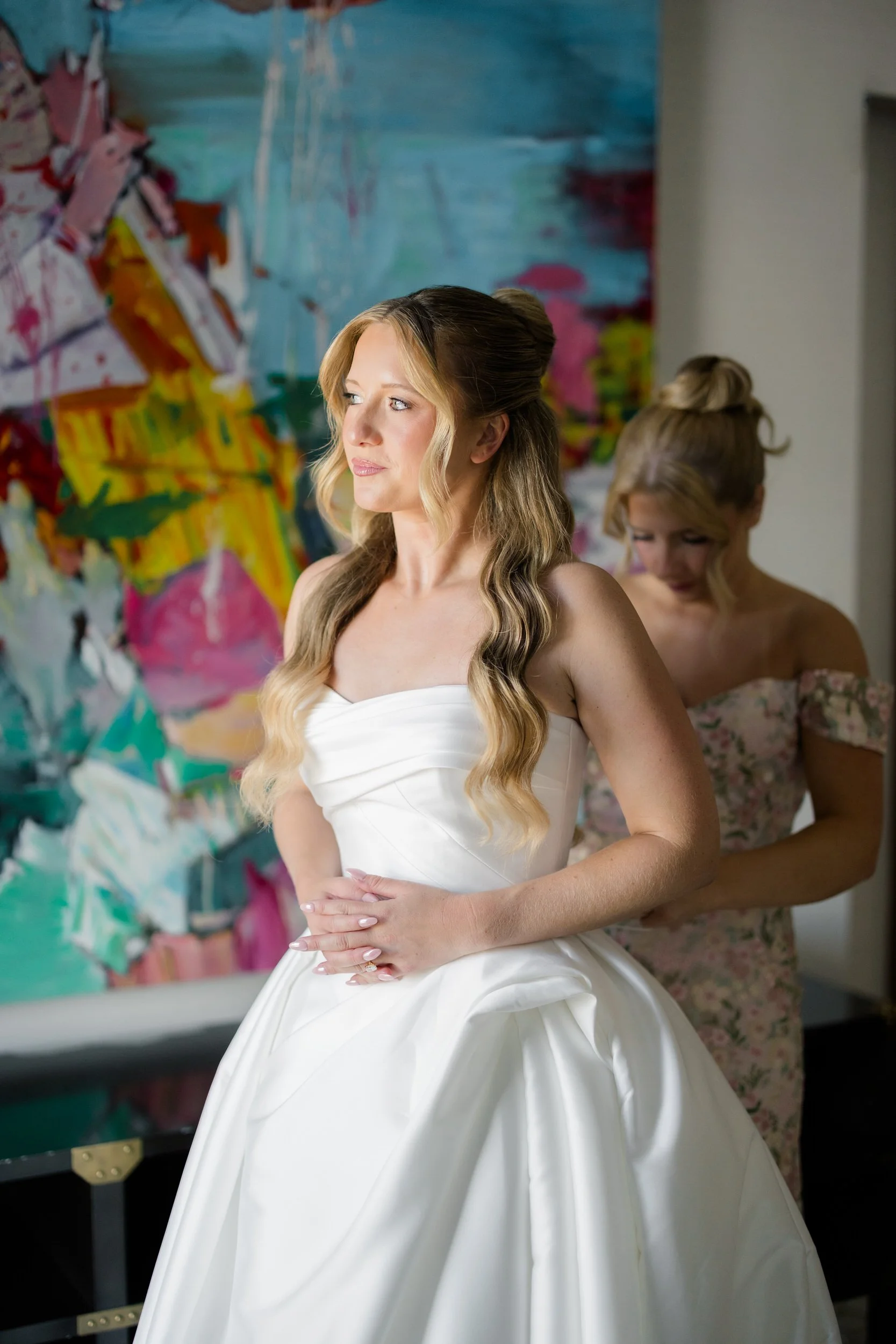Bride putting on her wedding gown at Hotel Commonwealth before a garden wedding celebration