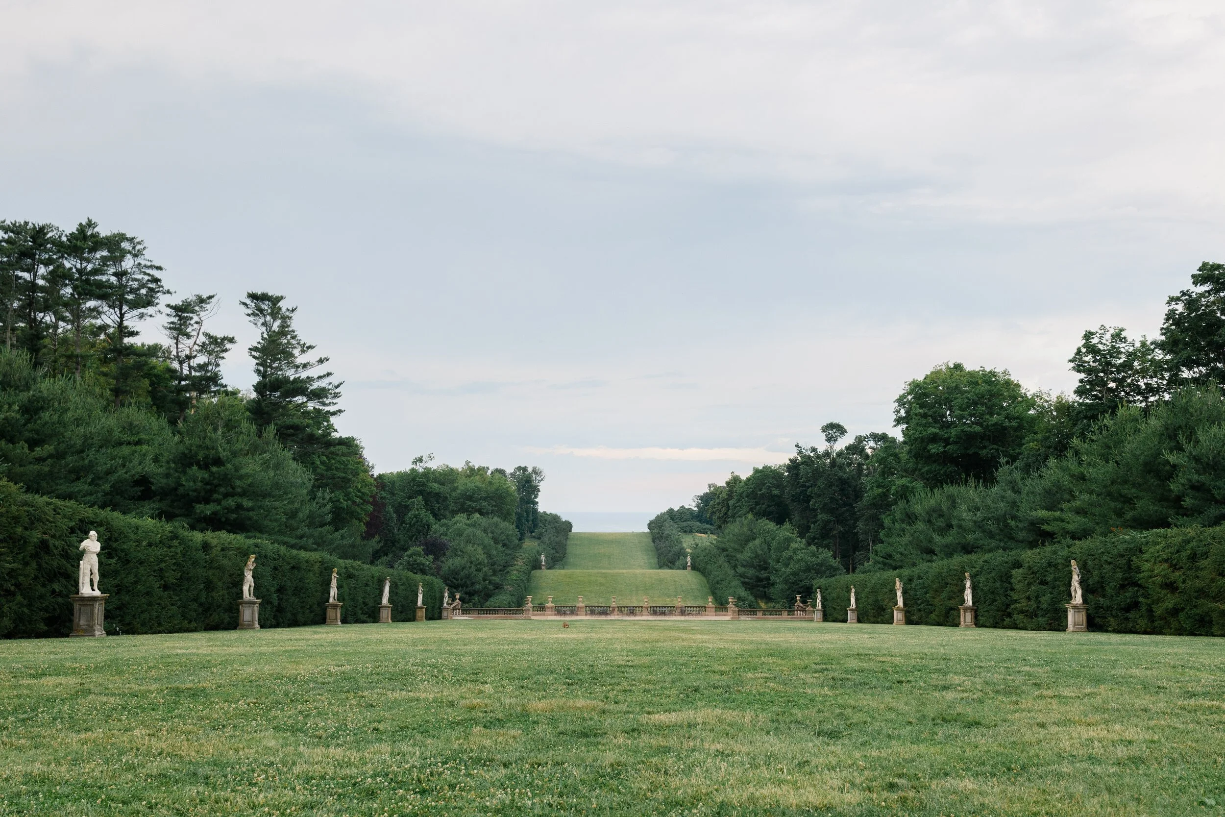 Unforgettable wedding cocktail hour on the Grand Allée featuring food stations, garden views, and a rainbow over the estate in Ipswich.