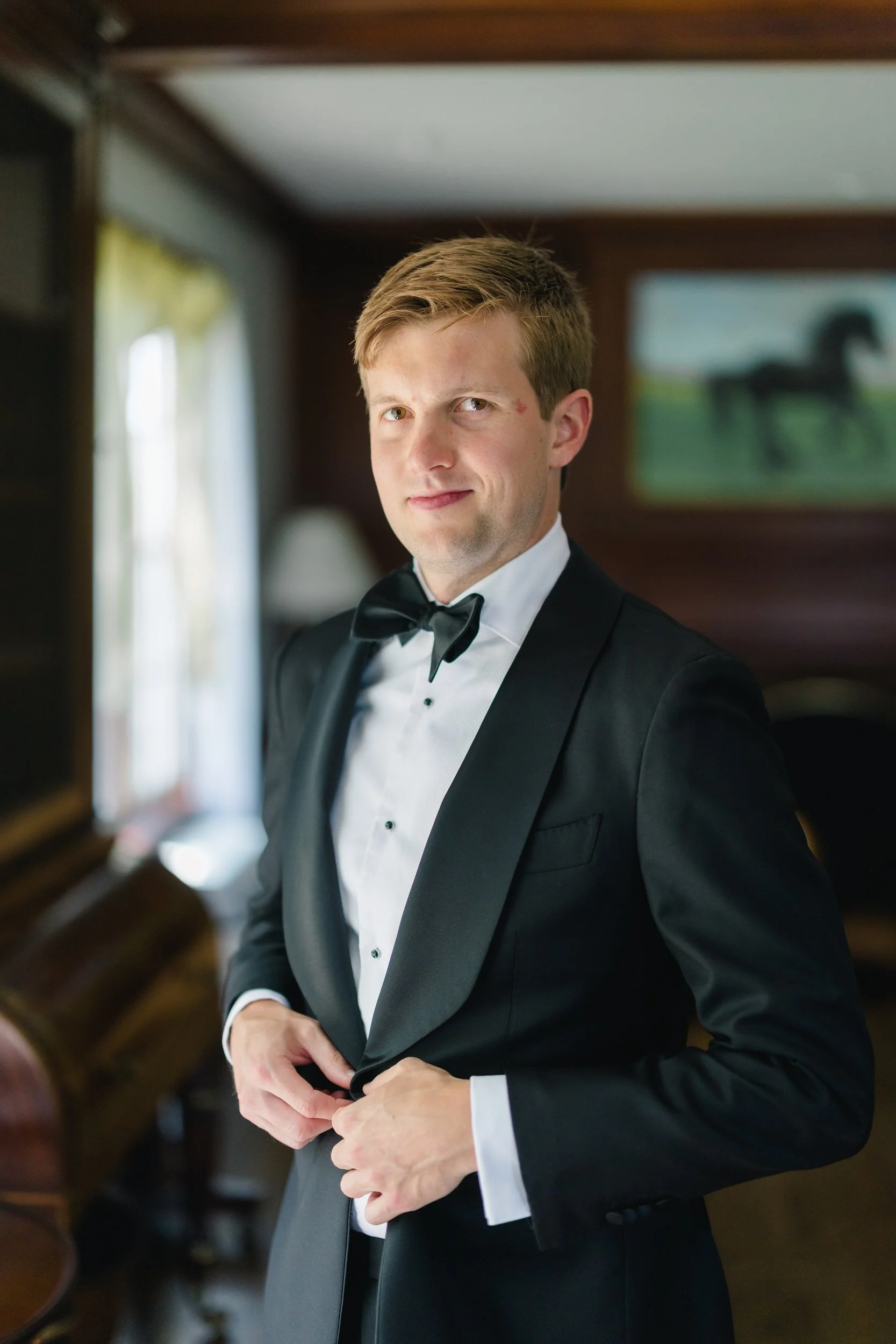Candid moment of the groom adjusting his suit and tie at Cedarwood Farm ahead of his Castle Hill on the Crane Estate wedding.