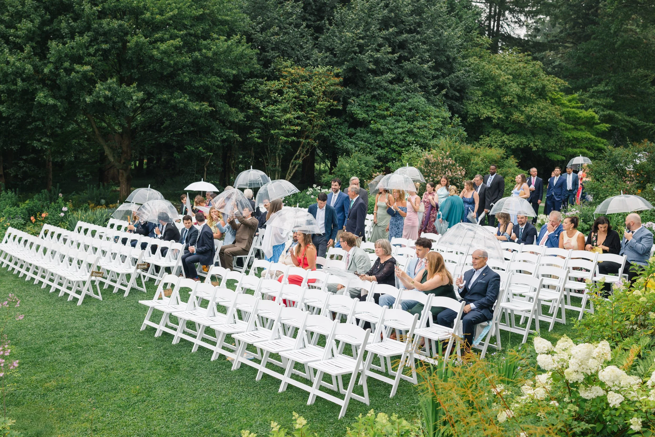 Ceremony chairs with white umbrellas arranged in the gardens at Blithewold Mansion & Gardens.