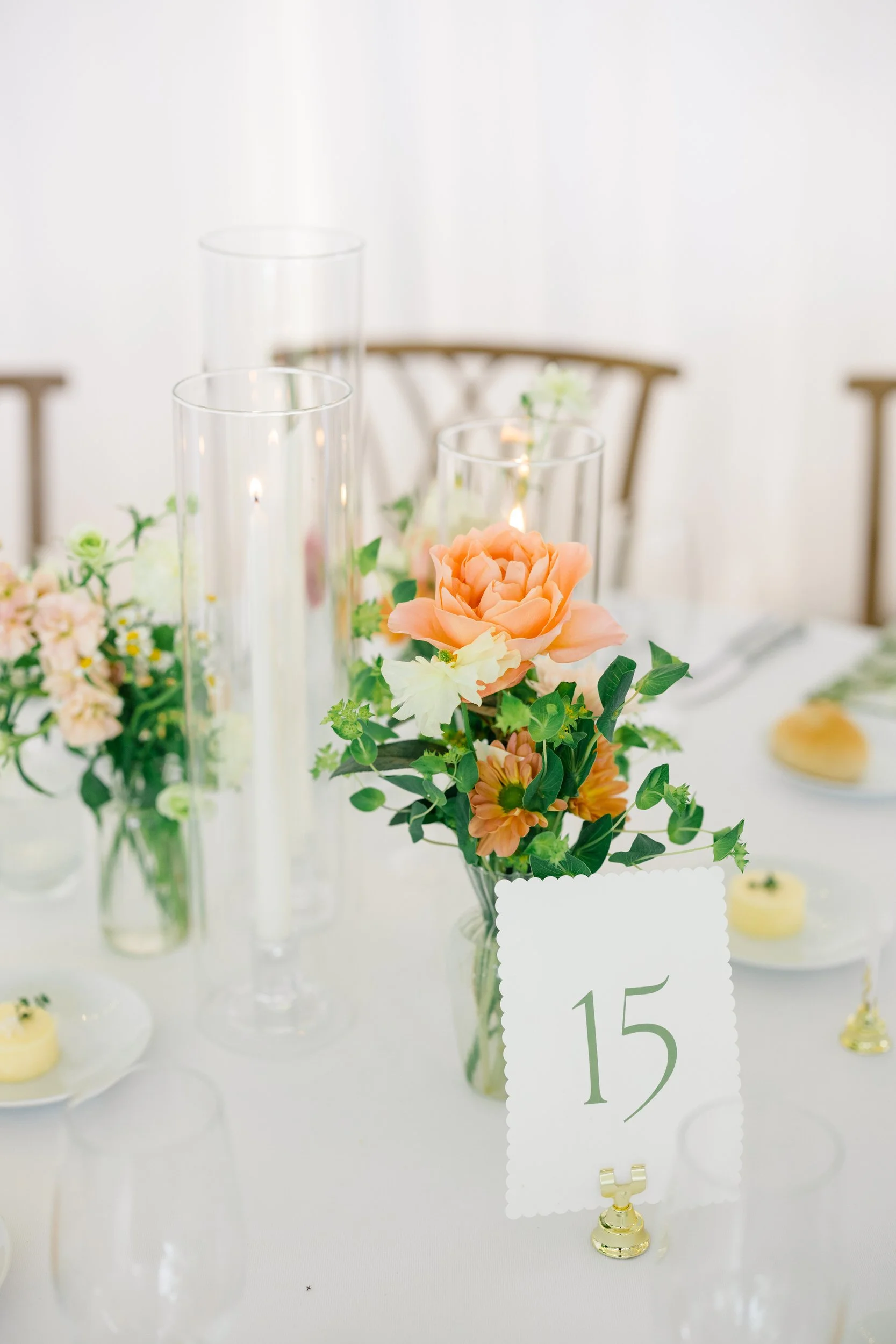 Reception table featuring orange, yellow, pink, and green floral arrangements.