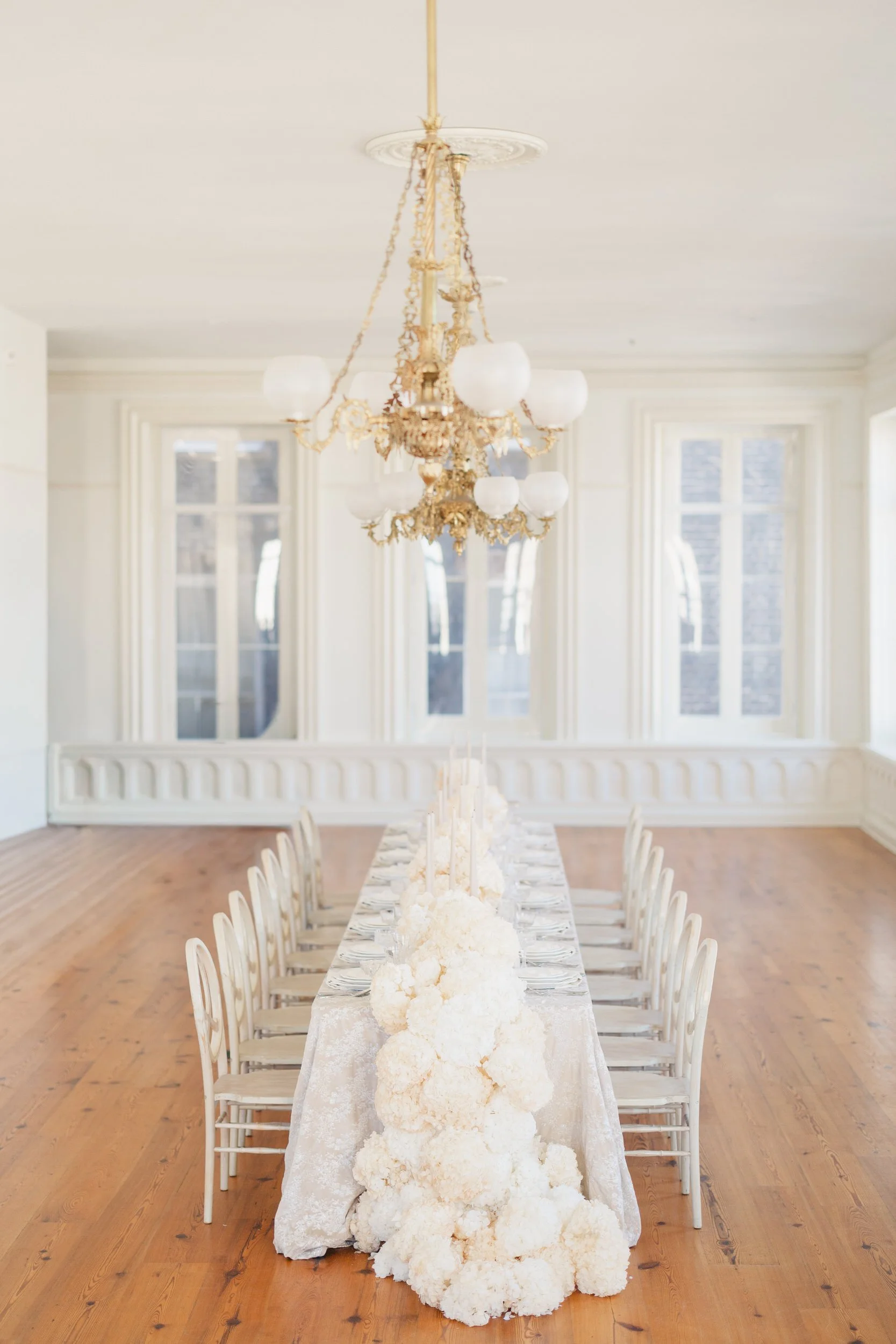Candlelit wedding reception at Brasserie La Banque in Charleston, SC featuring neutral floral arrangements and chic table design, photographed by a Charleston wedding photographer