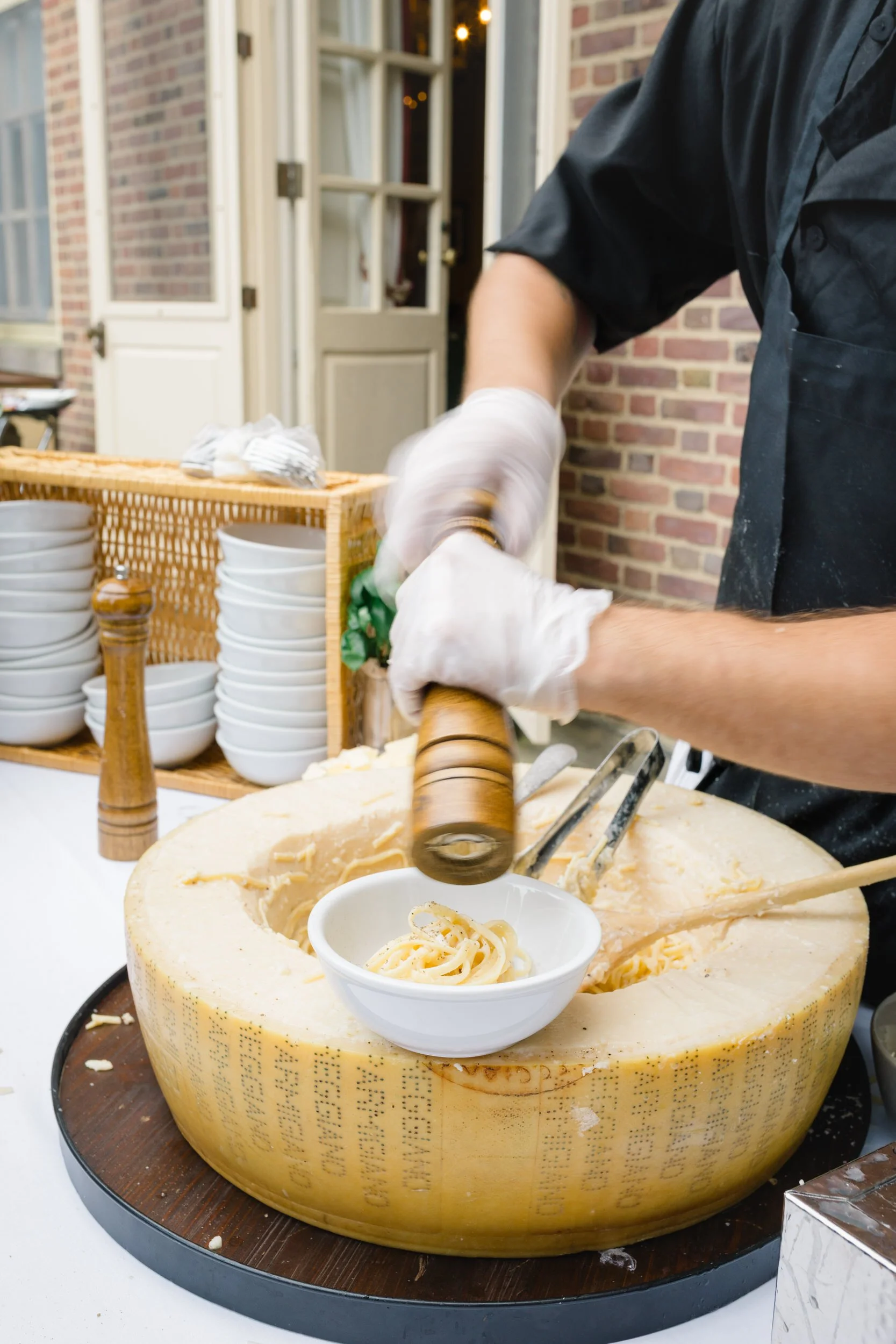 Live culinary experience featuring cacio e pepe pasta made inside a Parmesan wheel during a luxury wedding cocktail hour at Castle Hill.