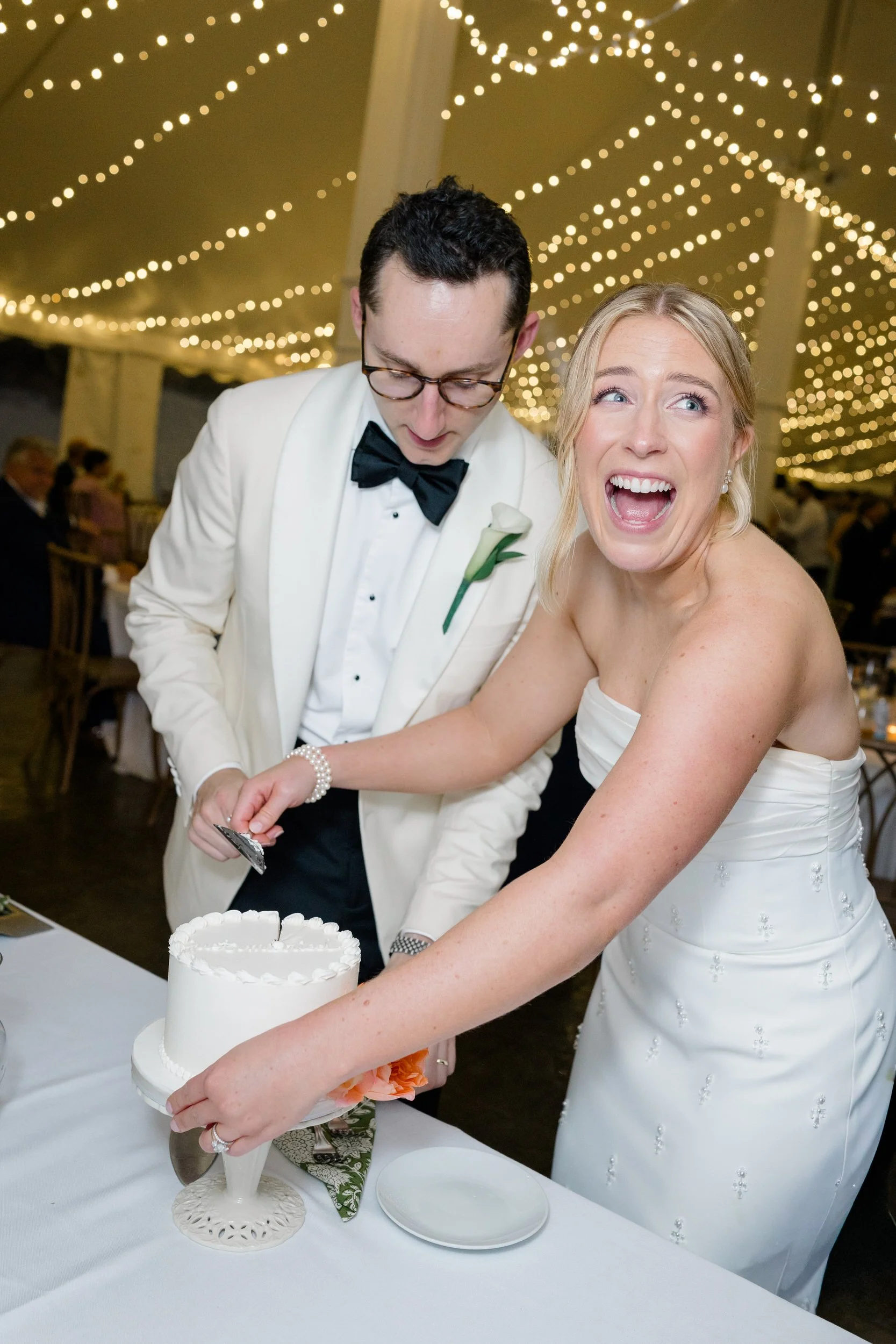 Couple laughing during cake cutting at their Rhode Island wedding.