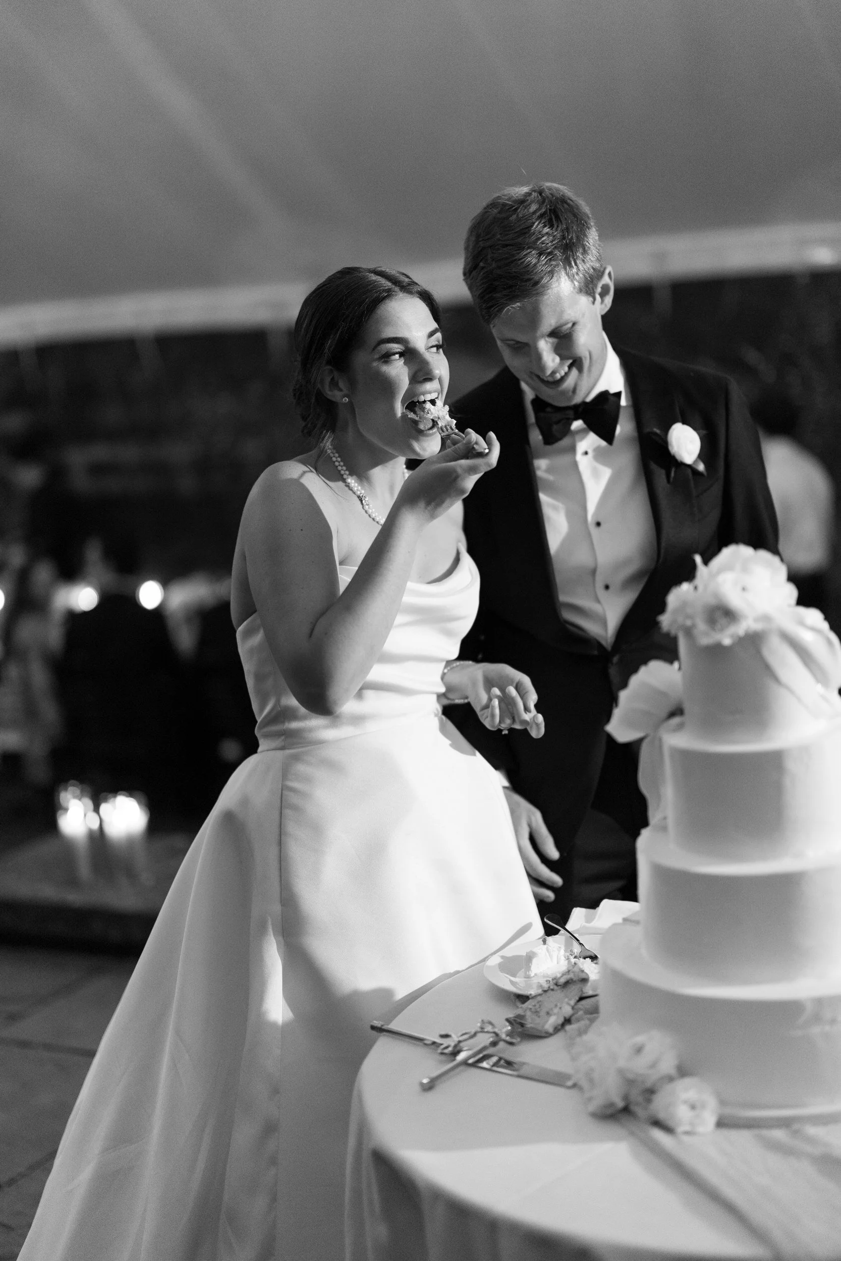 Couple feeding each other cake during their wedding celebration at Castle Hill on the Crane Estate.