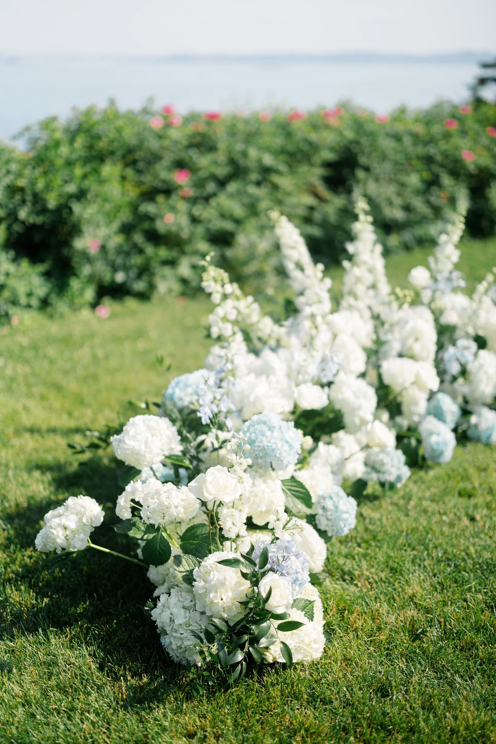 Elegant wedding ceremony setup with coastal views and summer florals.