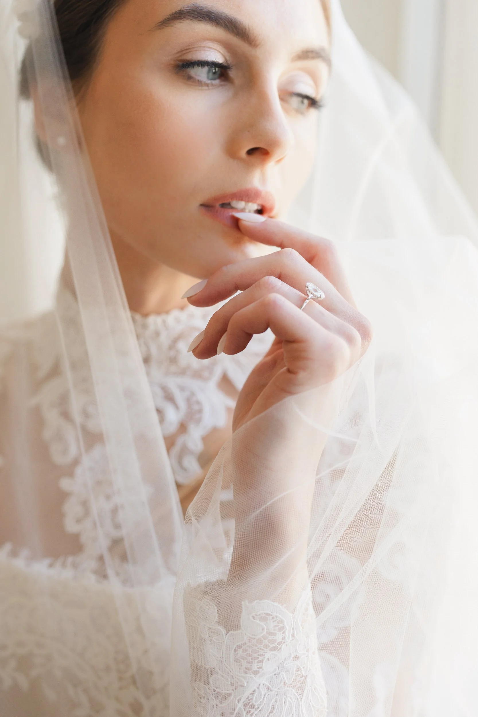 Chic bride in ivory and cream tones posing at a reception table at Brasserie La Banque, Charleston SC, photographed by a Charleston wedding photographer.