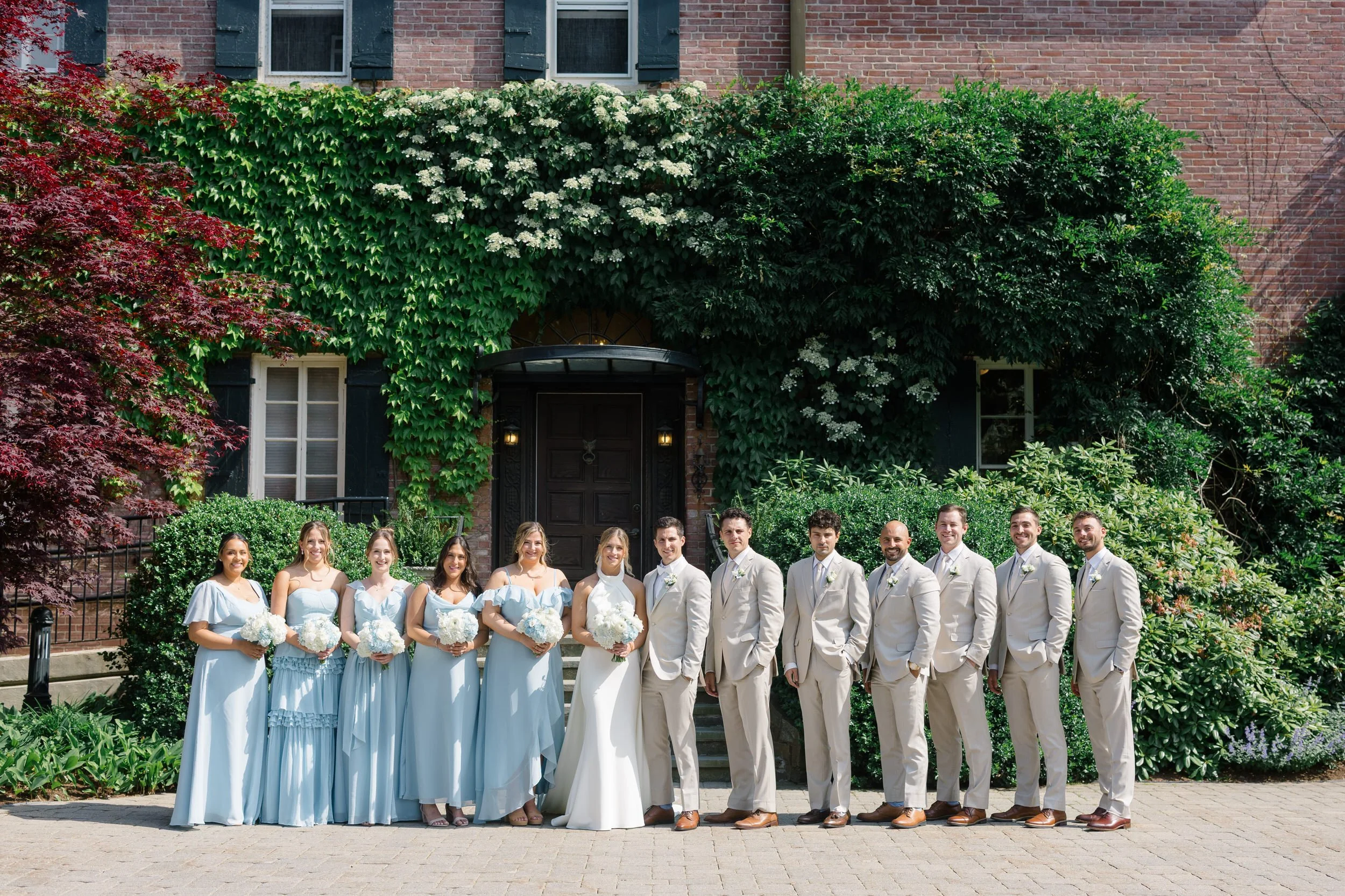 Bride and groom surrounded by friends during wedding party portraits.