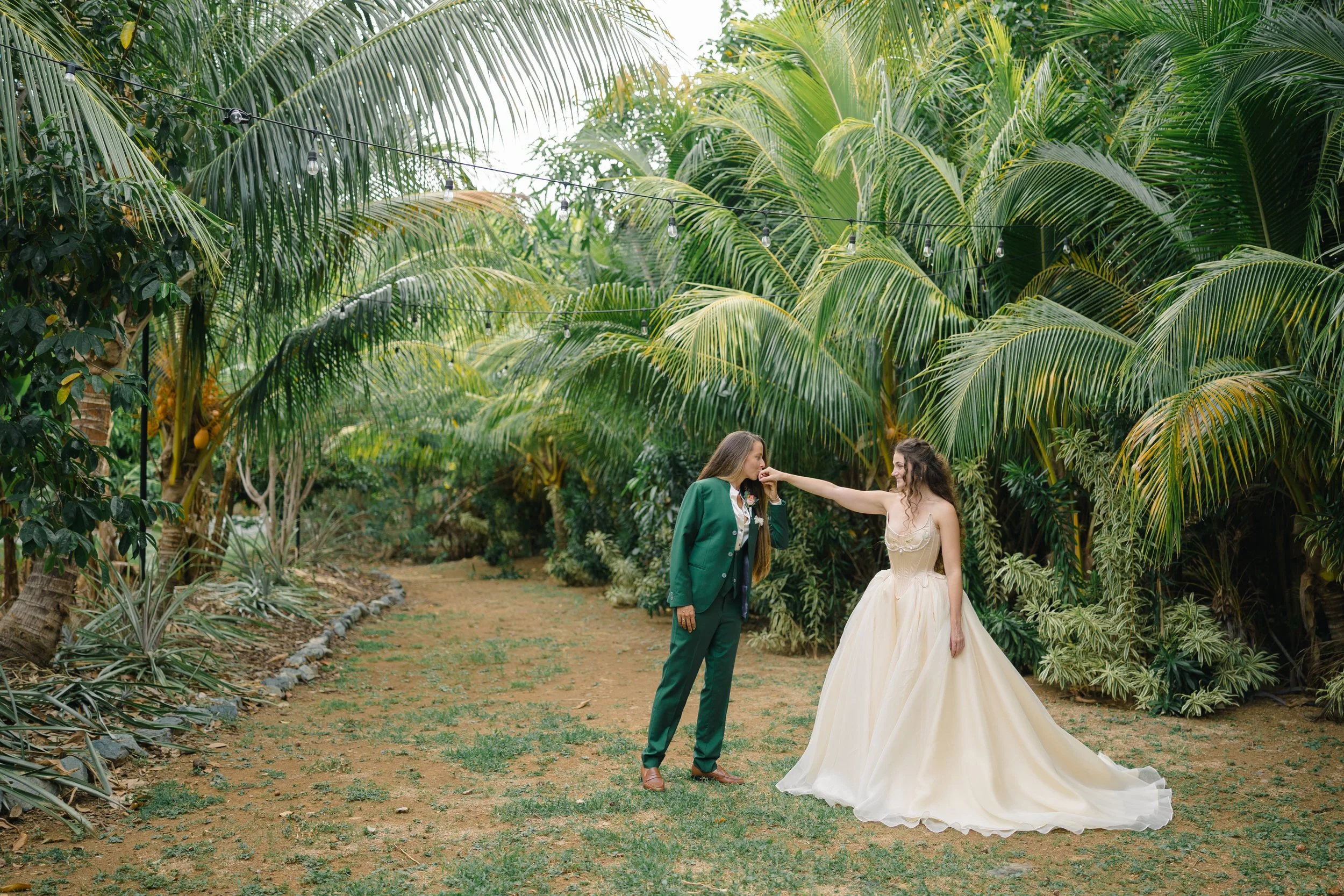 Bride in a handmade silk gown and bride in a green suit during their first look.