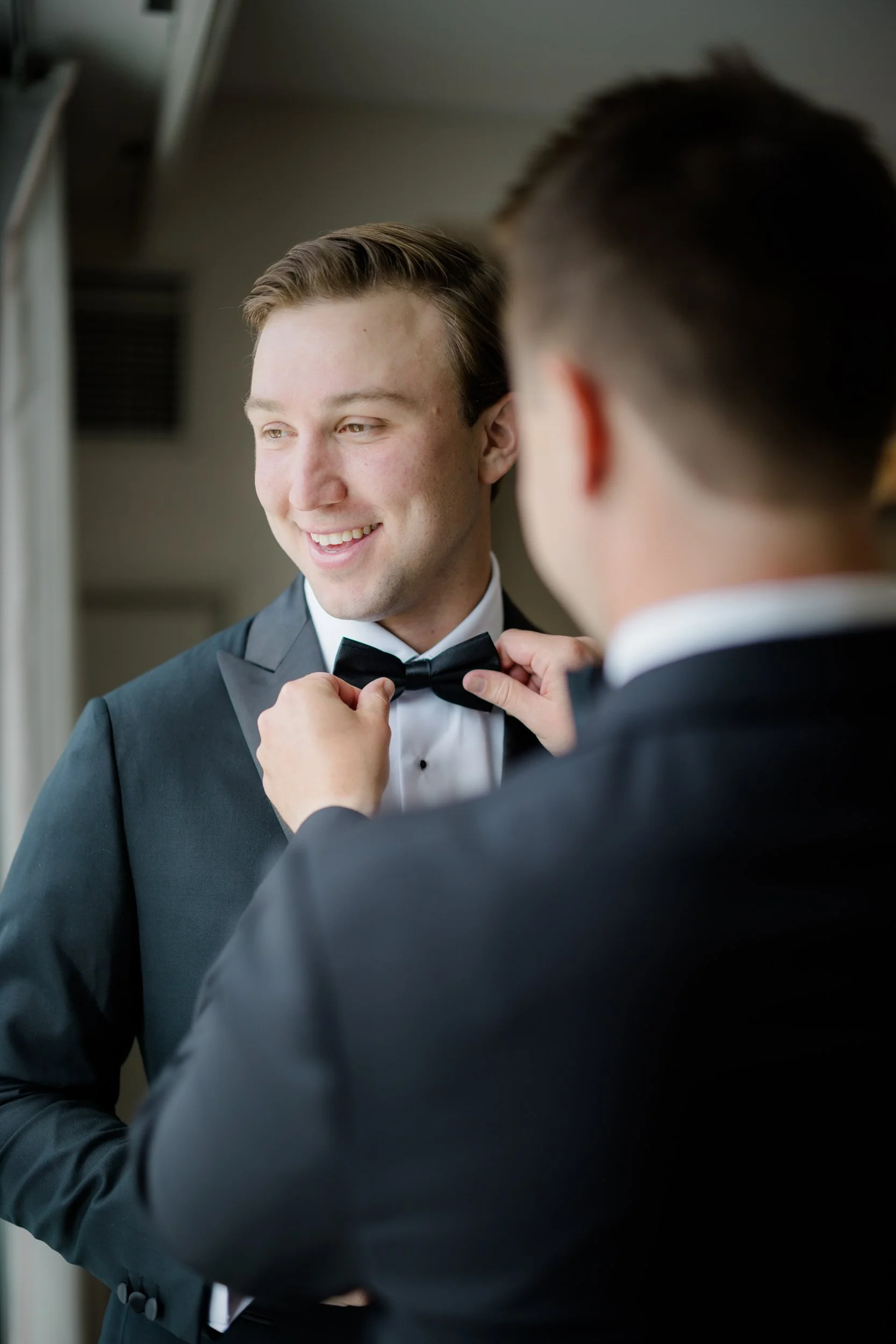 Groom putting on his suit before a garden wedding at The Gardens at Elm Bank