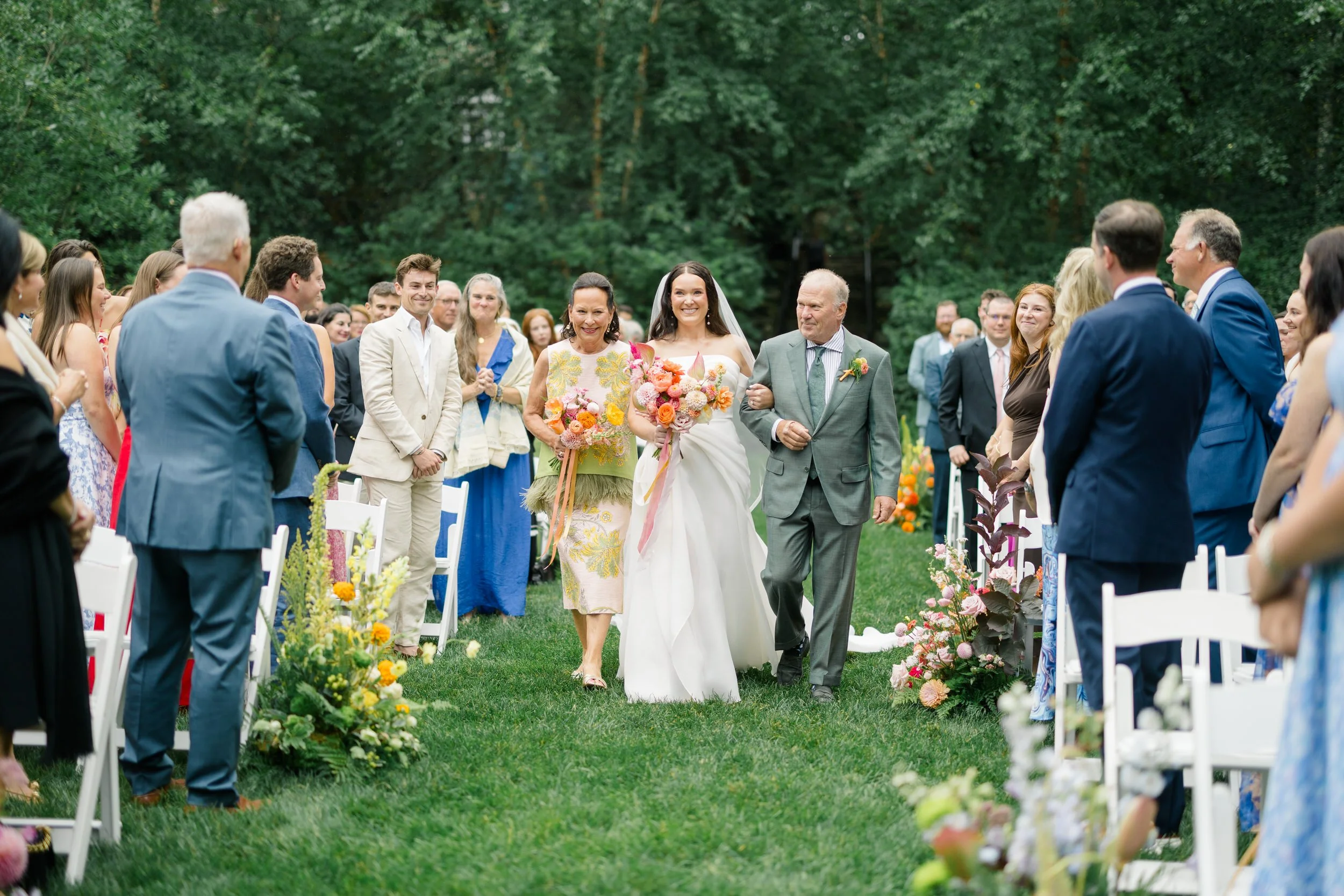 Bride walking down the aisle through a whimsical secret garden ceremony filled with colorful flowers.