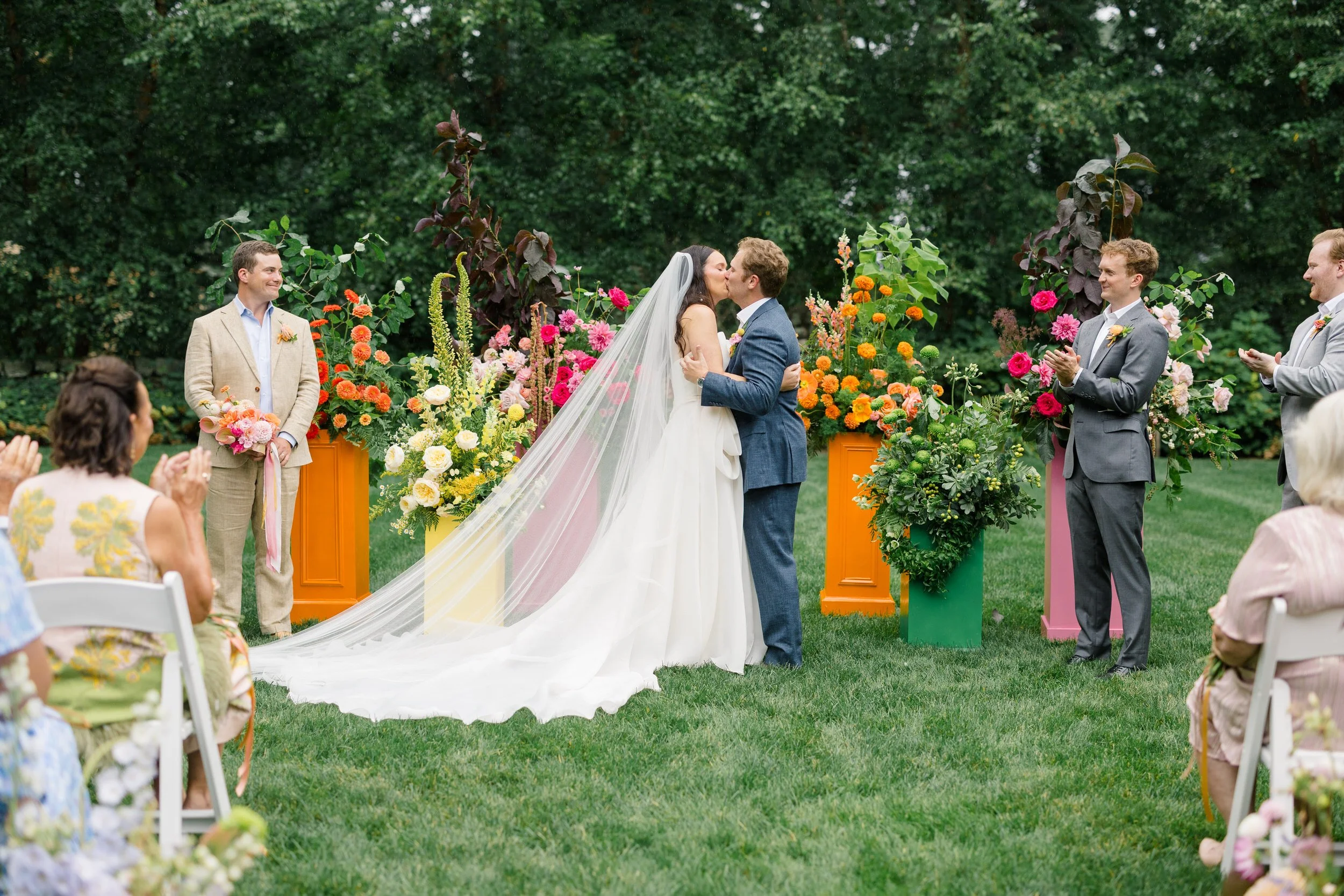 Colorful wedding ceremony surrounded by saturated pink, red, orange, and yellow blooms.