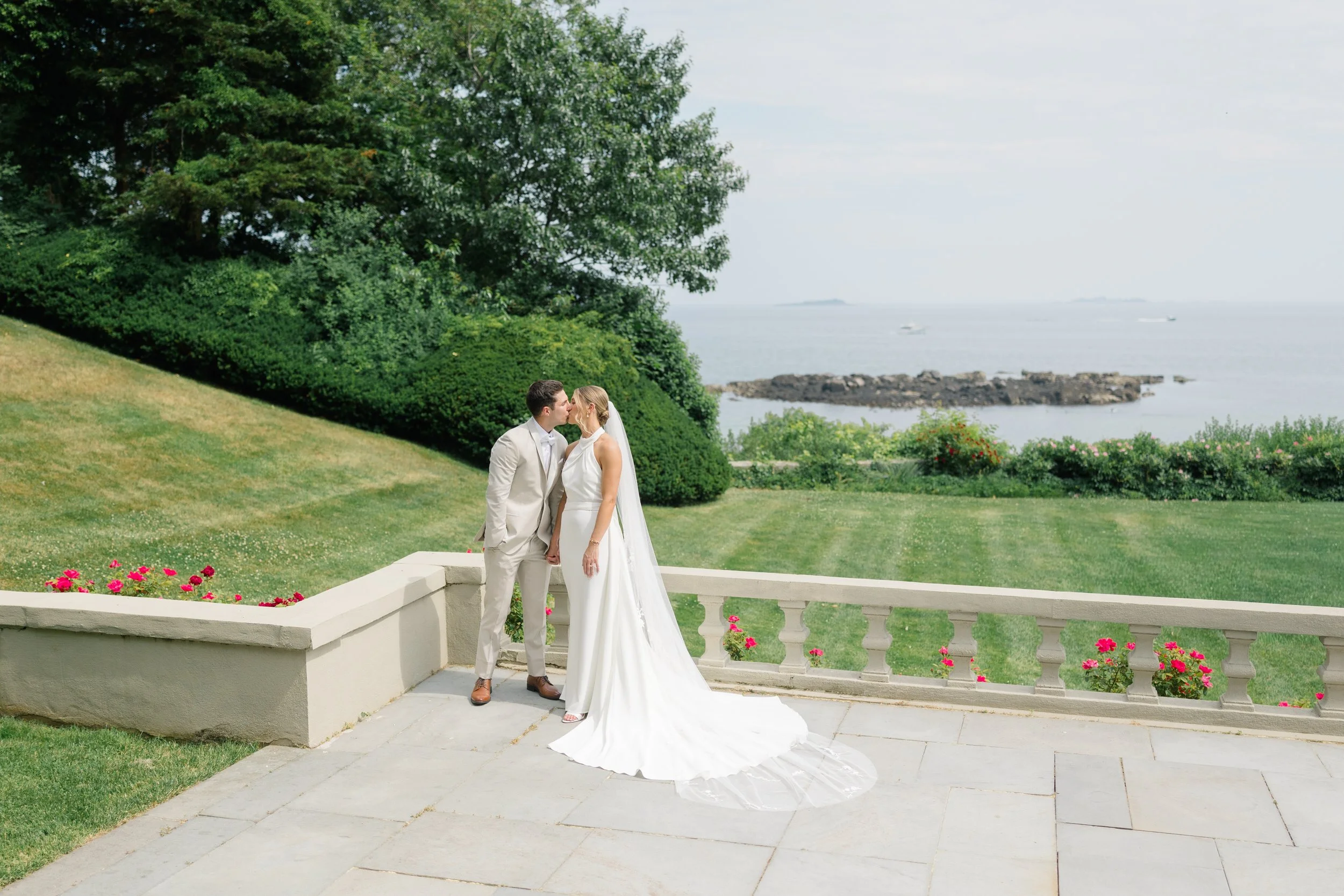 Bride and groom embracing with waterfront views in Beverly, Massachusetts.