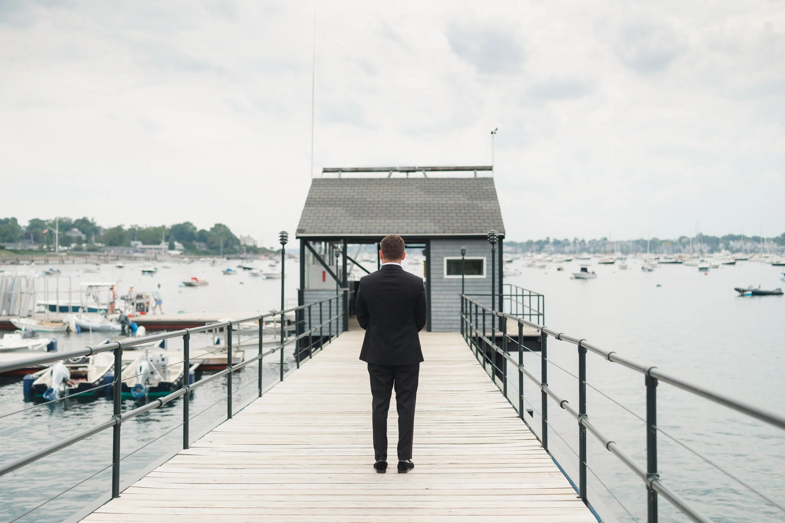 A romantic first look on the dock at Corinthian Yacht Club in Marblehead overlooking the sail-filled harbor.