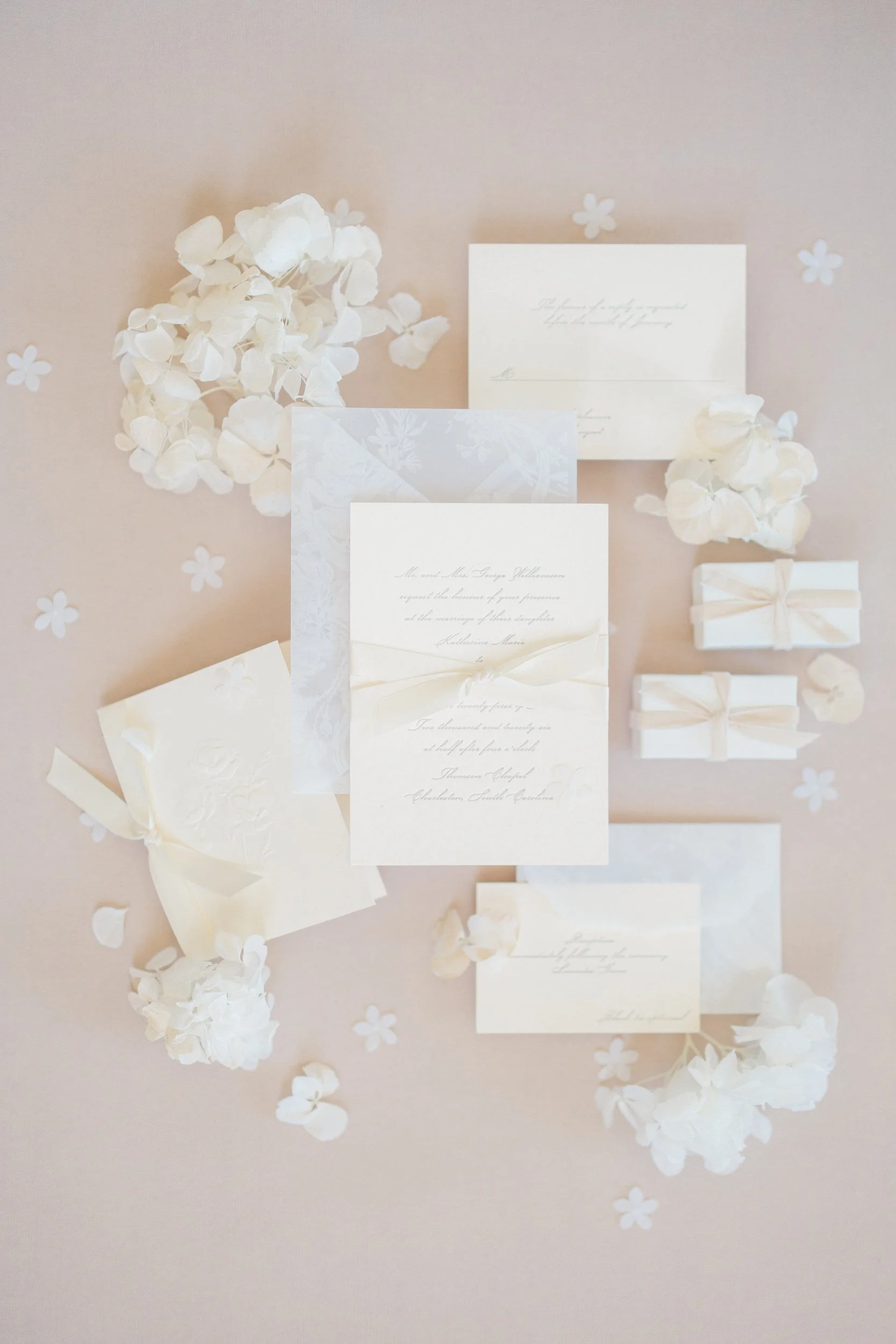 Elegant neutral flat lay of bridal details at Brasserie La Banque in Charleston, SC, including wedding invitation, rings, and accessories captured by a Charleston wedding photographer