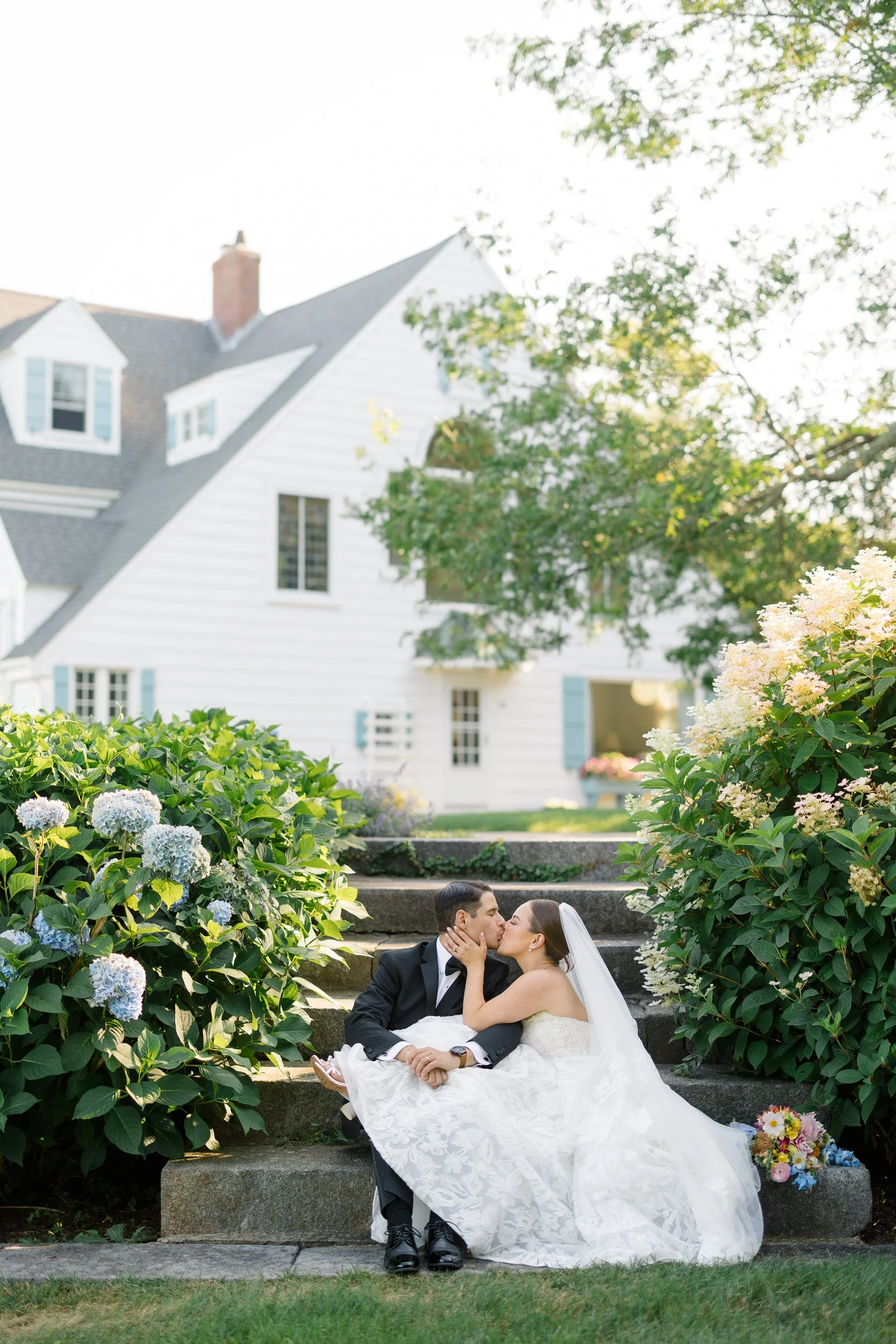Bride and groom surrounded by blooming hydrangeas during their Cape Cod private estate wedding.