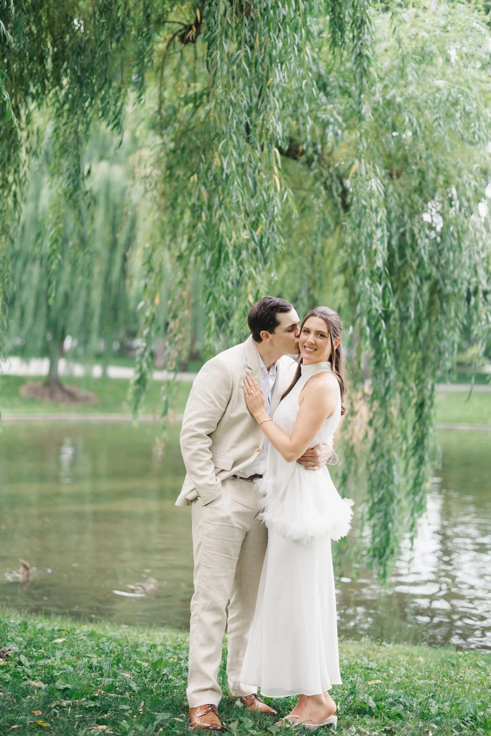 Couple strolling through the Boston Public Garden beneath lush summer trees.