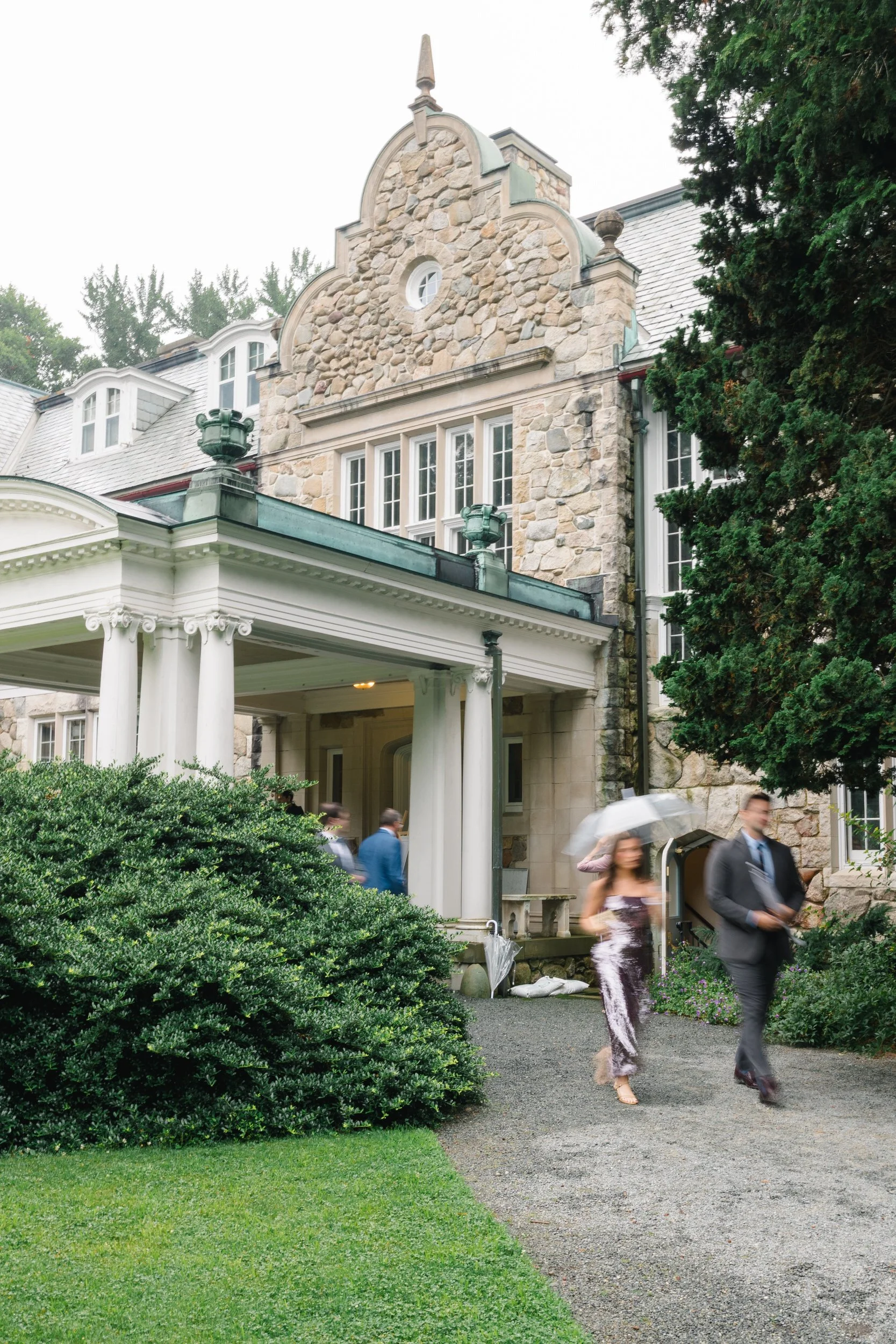 Rainy wedding ceremony setup with umbrellas at Blithewold Mansion.