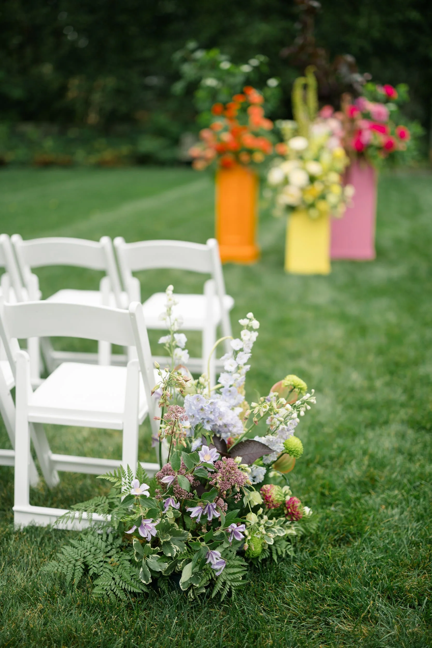 Colorful ceremony florals featuring pink, coral, orange, yellow, and red seasonal blooms.