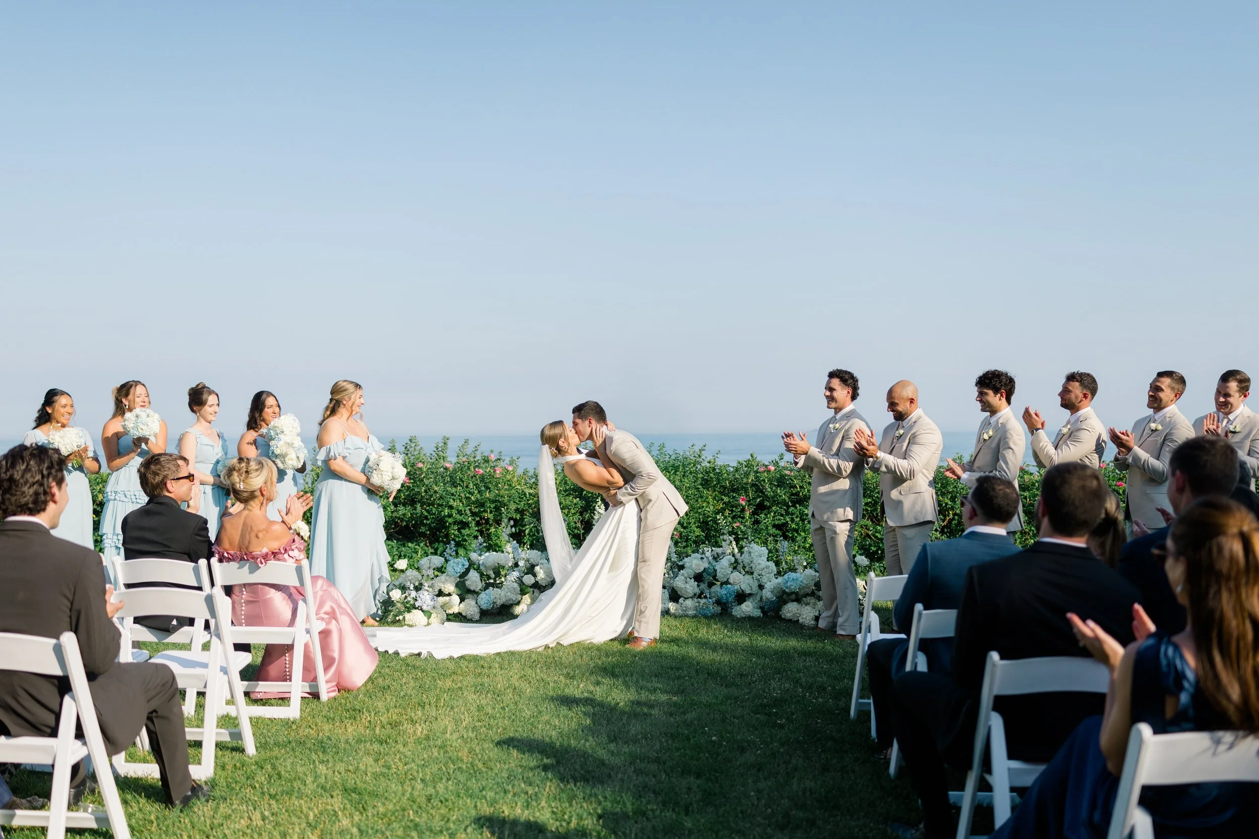 Couple sharing their first kiss as newlyweds during a coastal wedding ceremony.