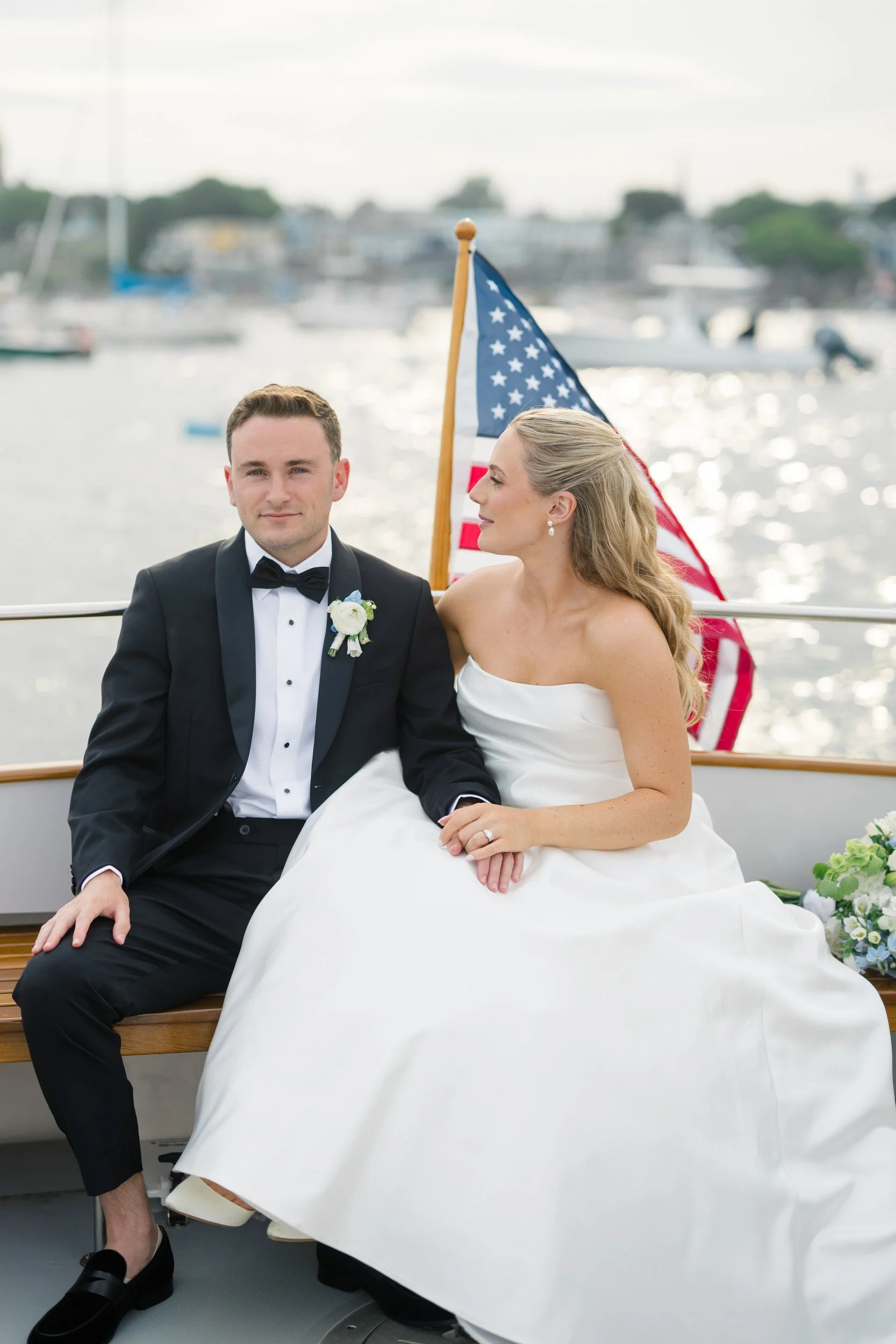 Couple traveling by boat between ceremony and reception during a coastal New England wedding at Corinthian Yacht Club.